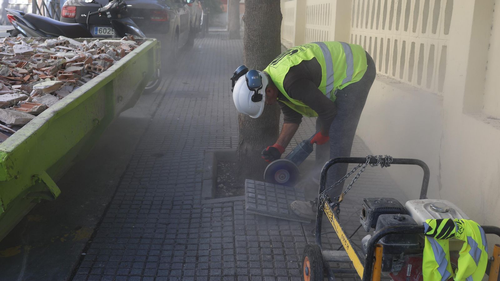 Un operario trabajando en la zona para arreglar el acerado.