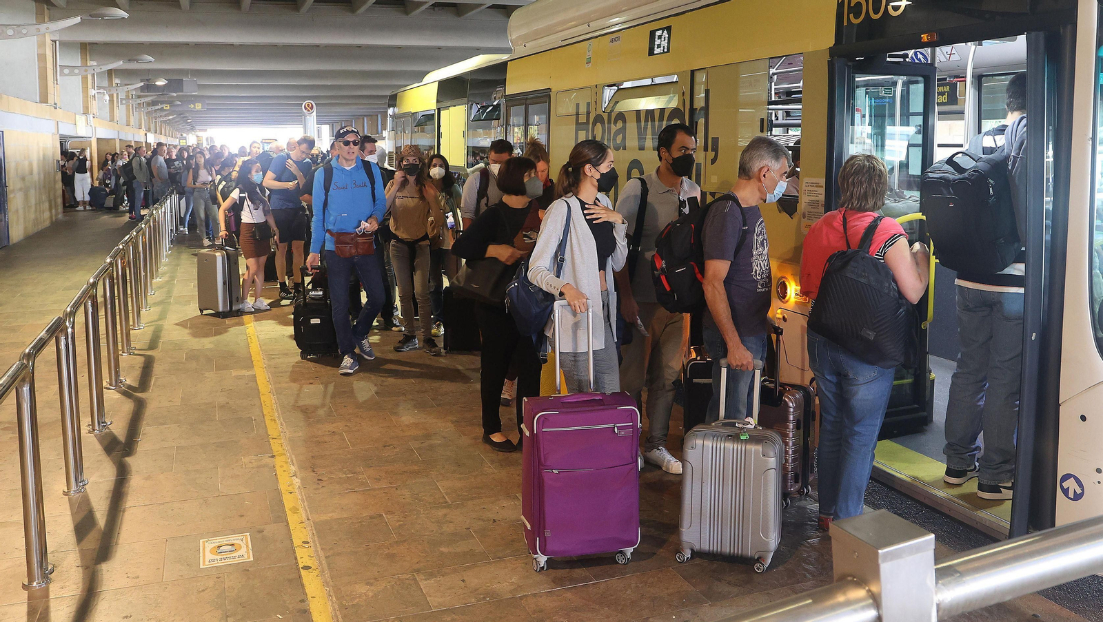 Larga cola de pasajeros para el autobús del aeropuerto, este viernes.