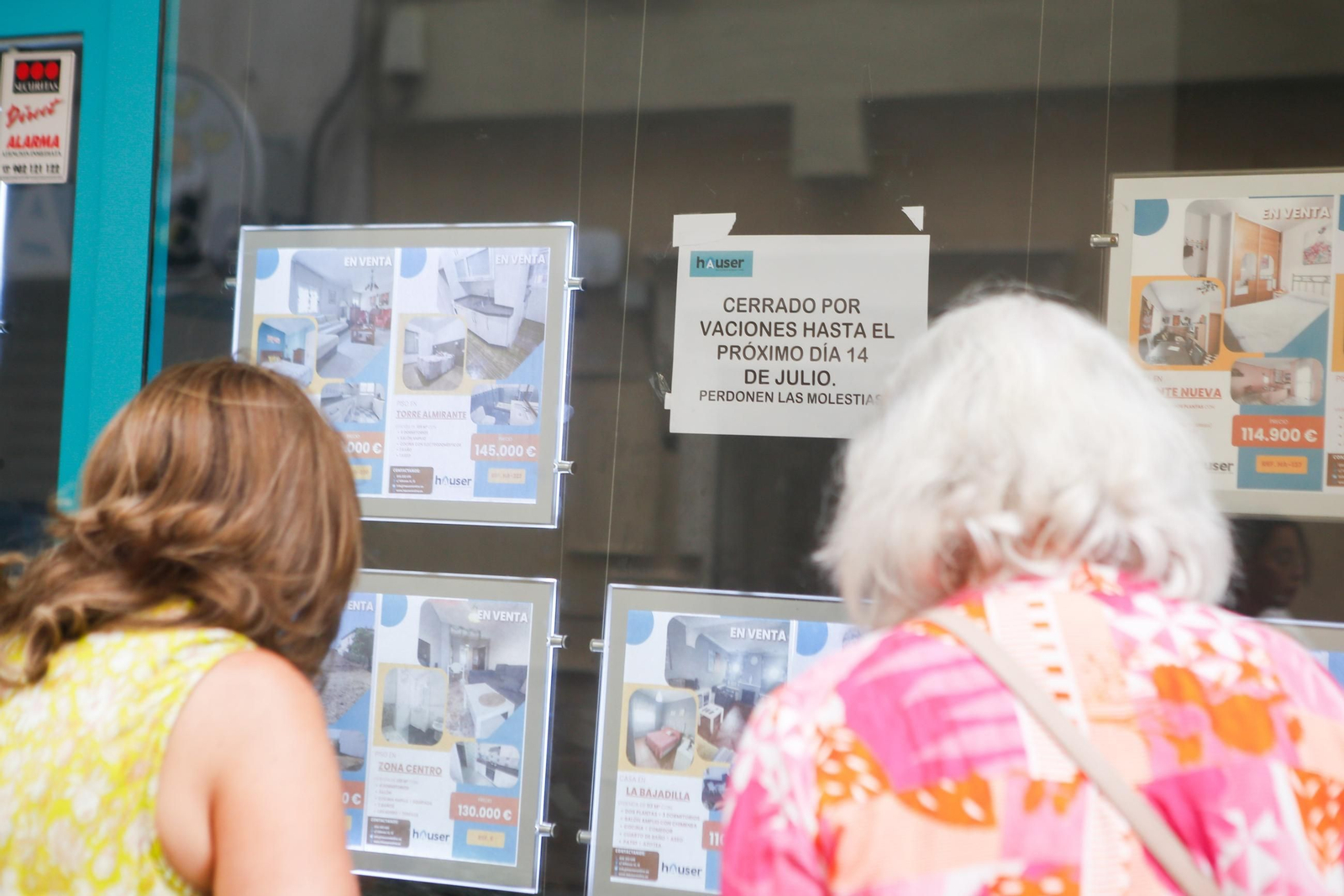 Dos mujeres observan el escaparate de la inmobiliaria Hauser.