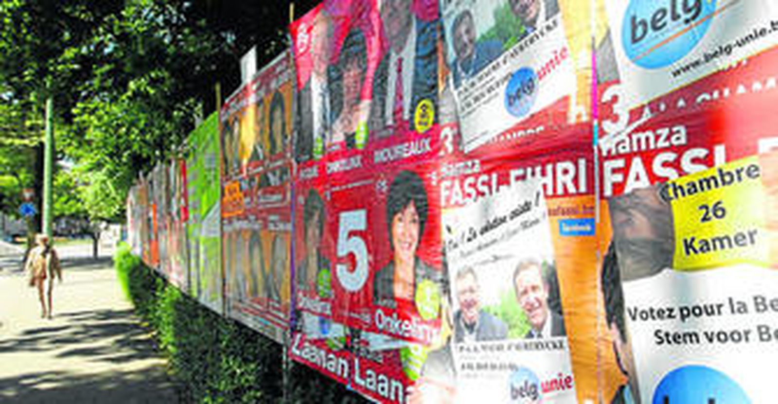 Una mujer camina ante una pared repleta de carteles electorales en Bruselas.