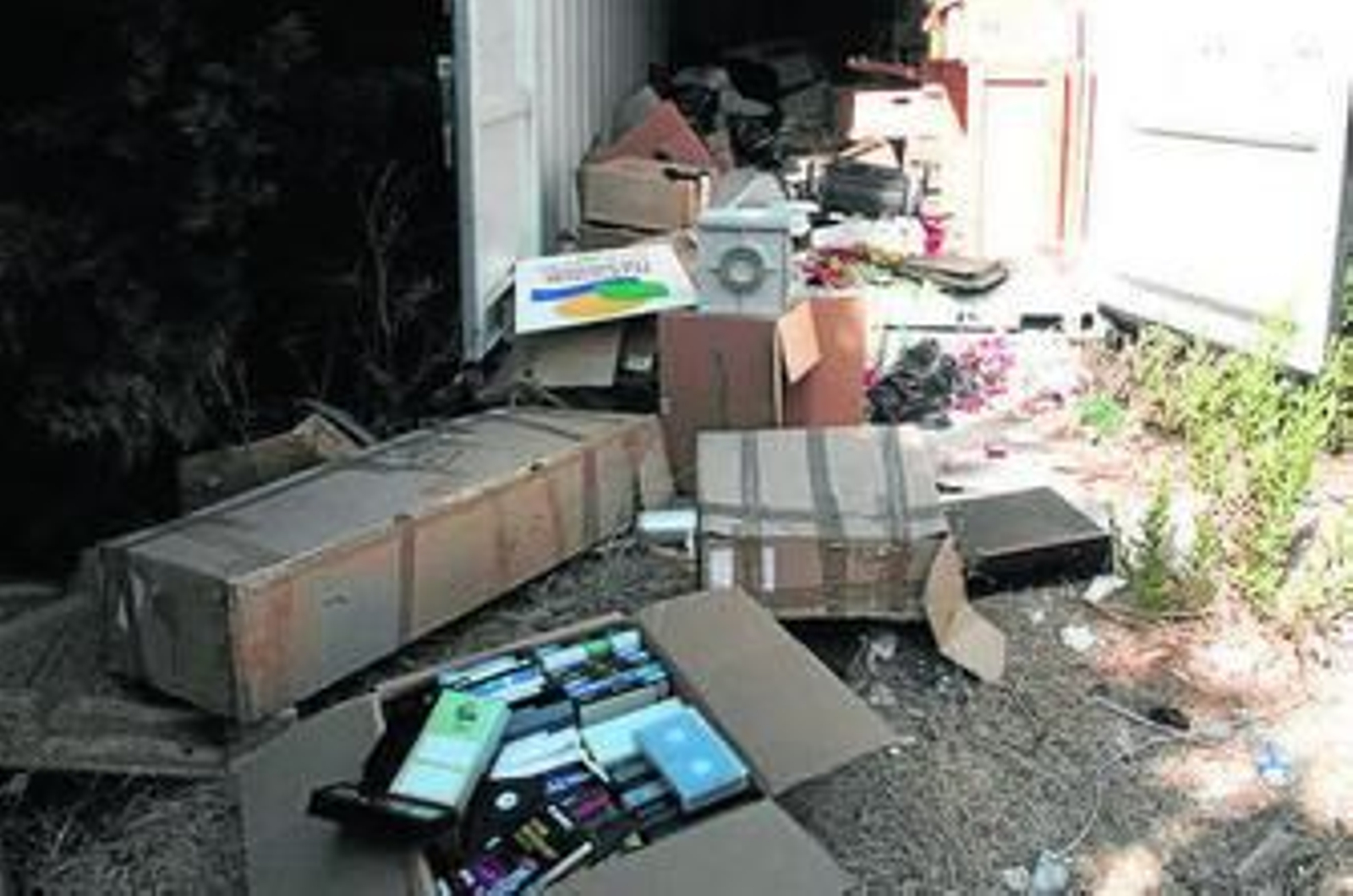 Cajas con cintas de vídeo y otros enseres junto a un contenedor.