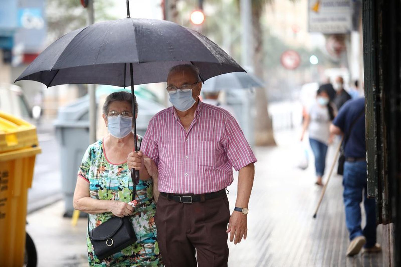 Dos personas andan este lunes por la calle guarecidos de la lluvia con un paraguas.