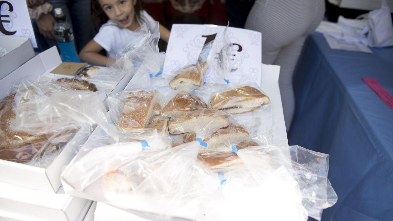 Una niña se relame junto a un puesto de tortas. Una niña se relame junto a un puesto de tortas.