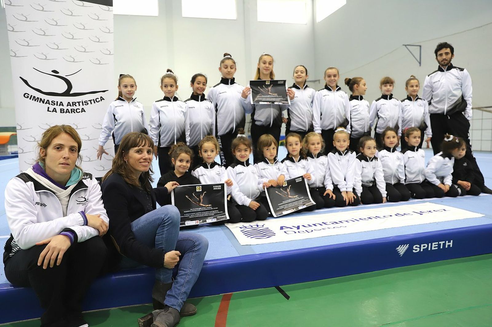 Laura Álvarez, con las gimnastas del CGA La Barca y el cartel anunciador de la prueba de este fin de semana.