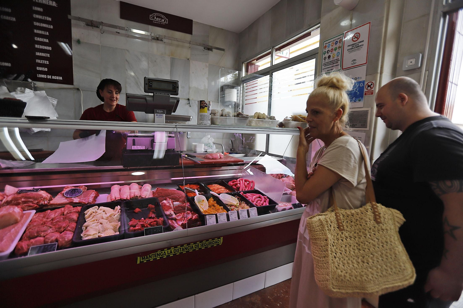 Varias personas esperan a ser atendidos por la dueña de la carnicería.