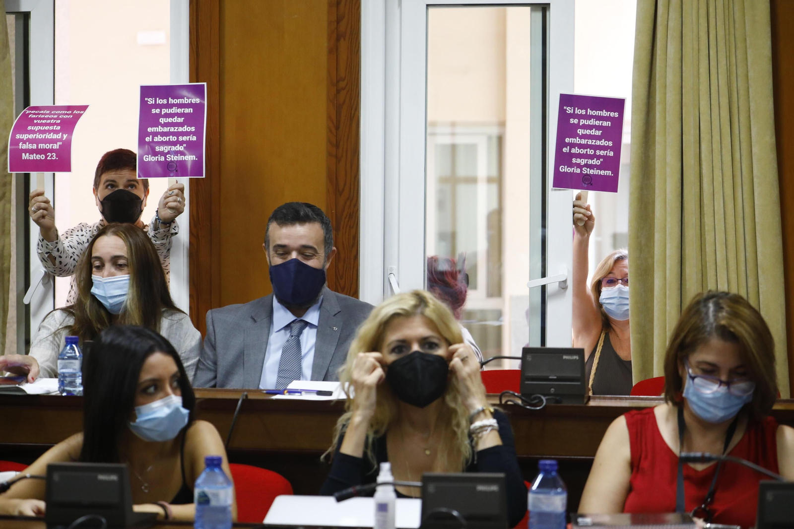 Unas mujeres sostienen unas pancartas a favor del aborto detrás de los ediles de Vox.