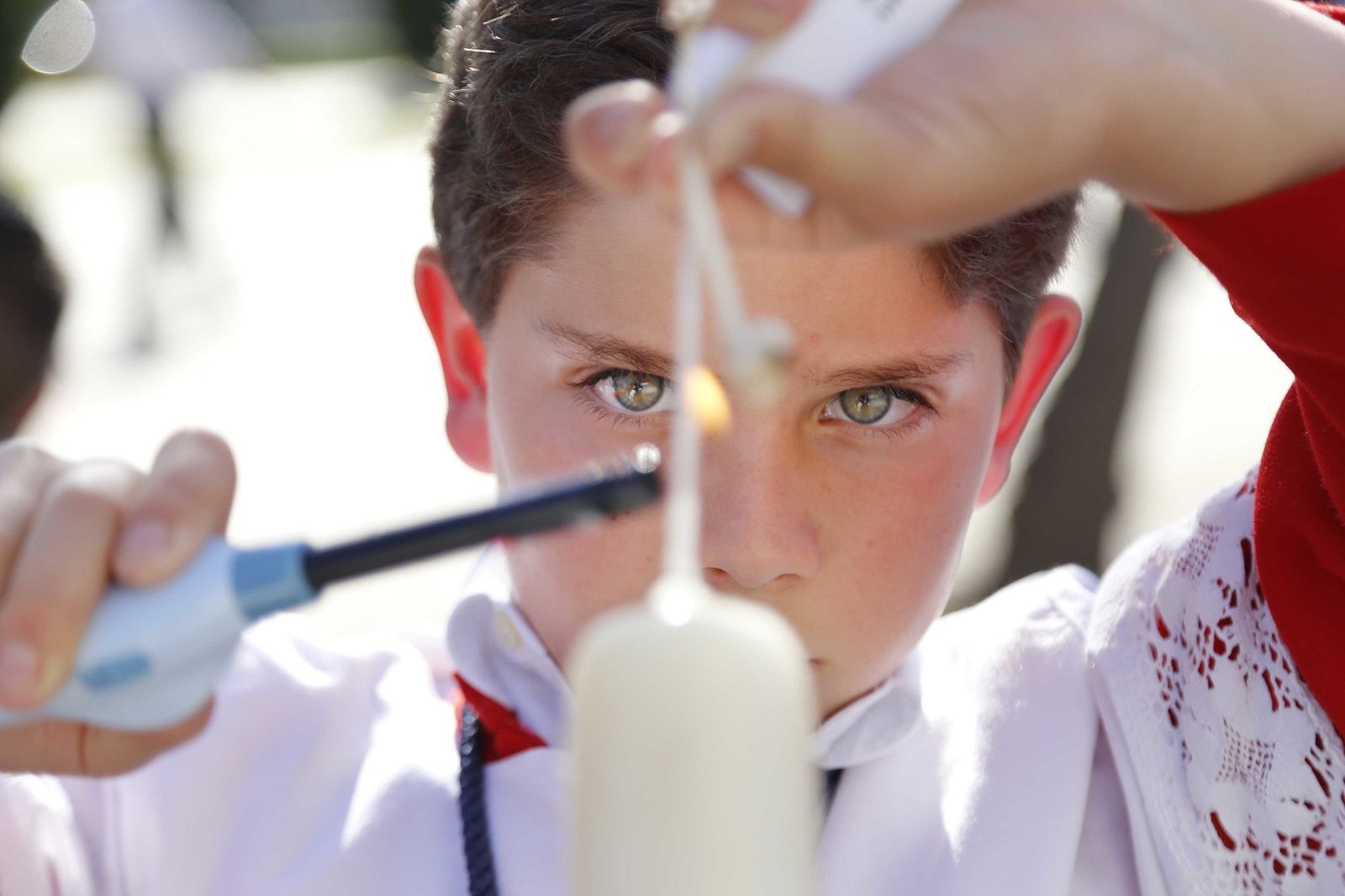 Un monaguillo, ayudado con encendedor electrónico, prende ayer el pabilo de un cirio.