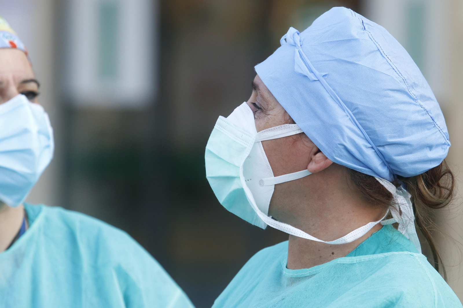 Dos profesionales sanitarias, protegidas con mascarillas y gorros.
