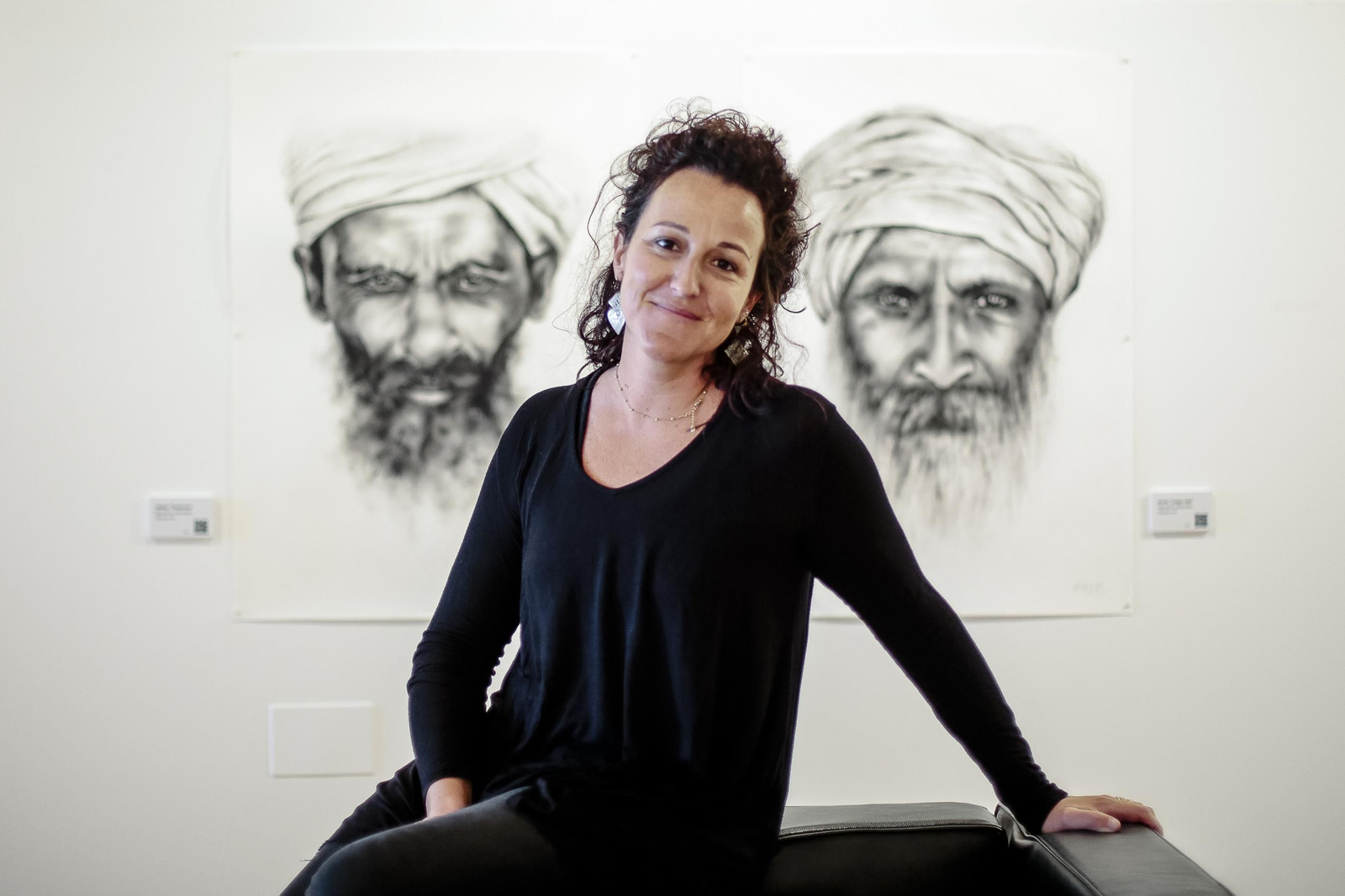 La artista Carmen López, ante dos de las obras de su exposición ‘Miradas’ que muestra en el Baluarte de San Roque de Cádiz.