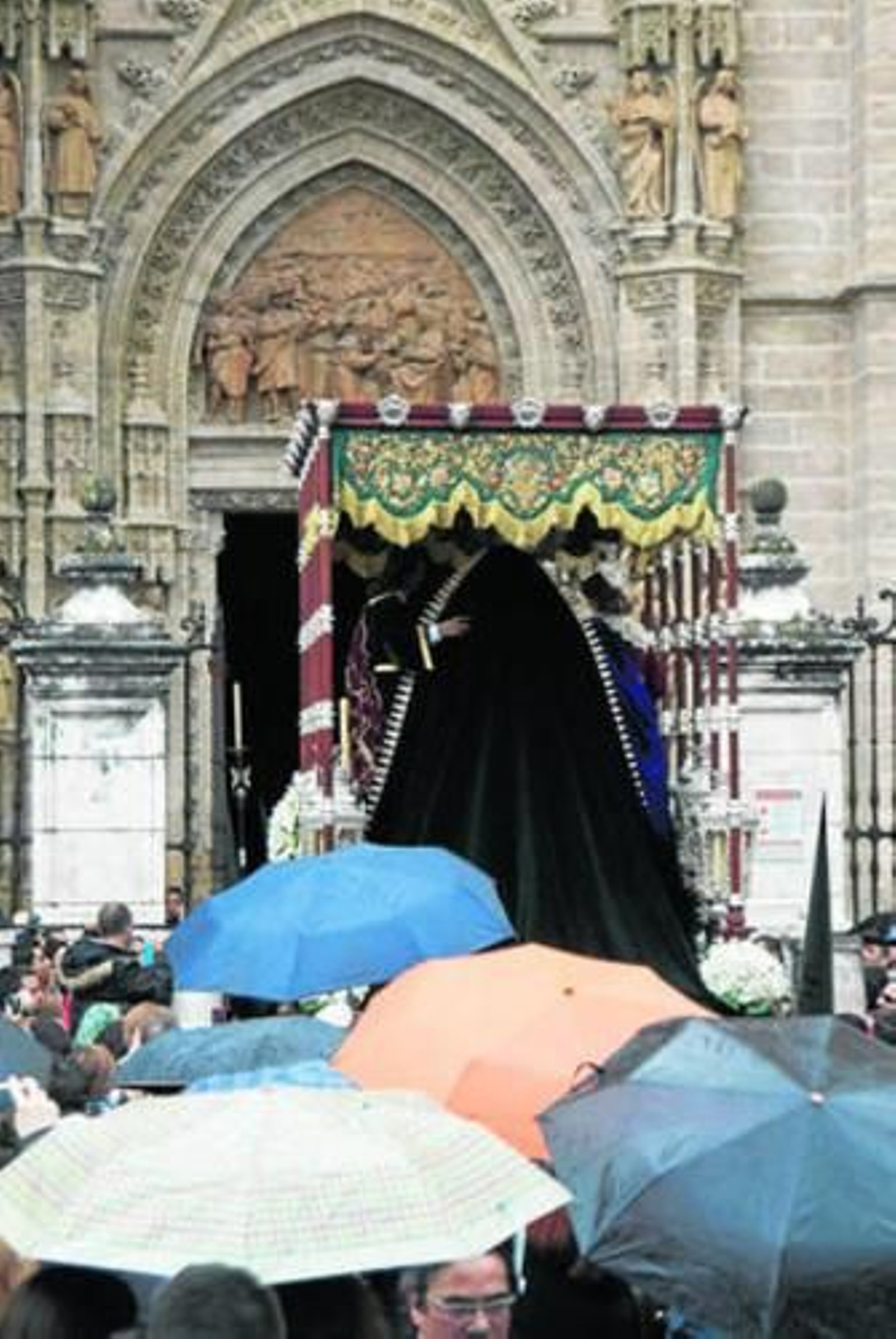 El paso de palio de la Virgen del Sol entra apresuradaente en la Catedral bajo un aguacero.
