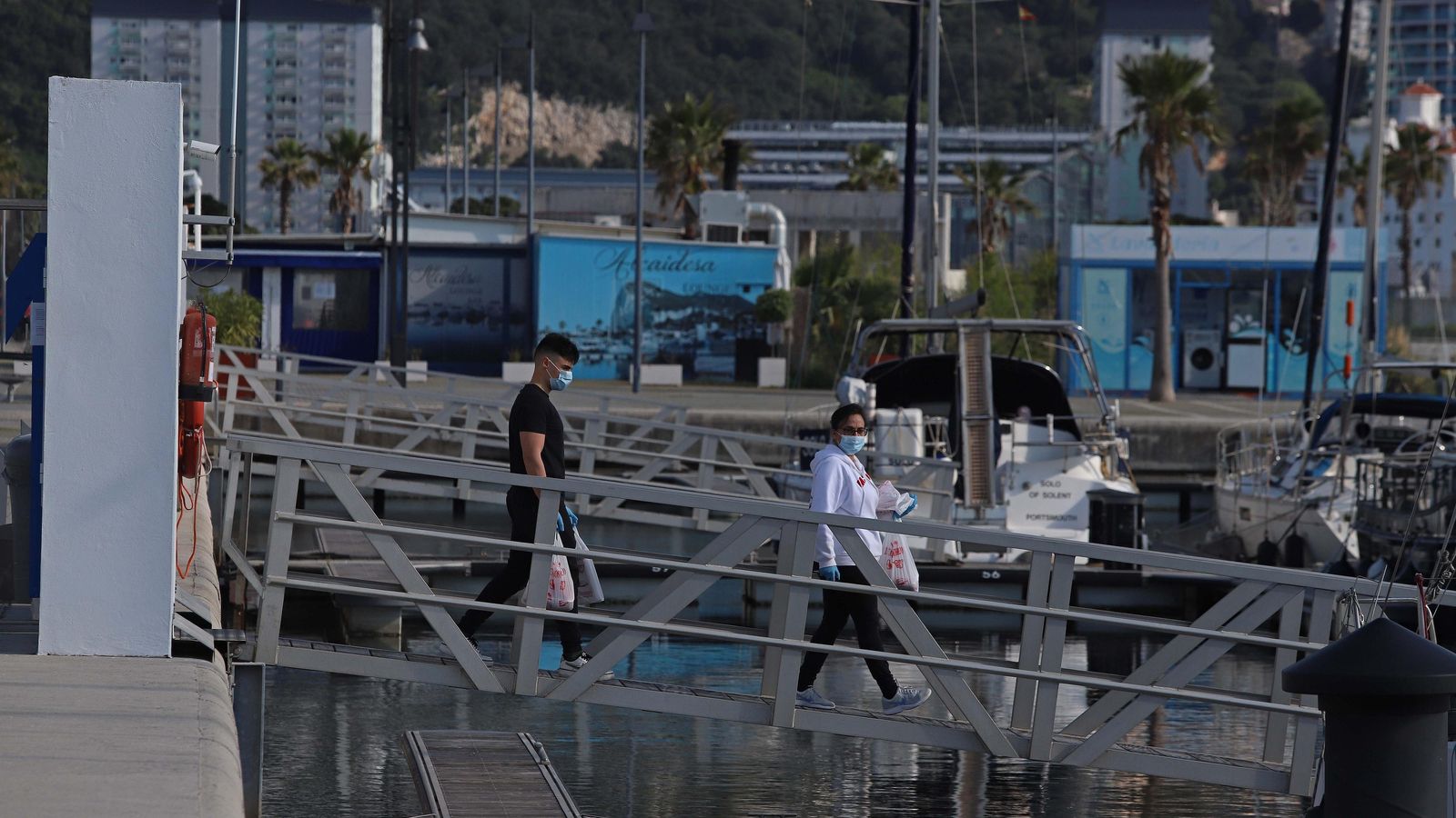 Dos personas se disponen a entregar un pedido de alimentos a una de las embarcaciones.
