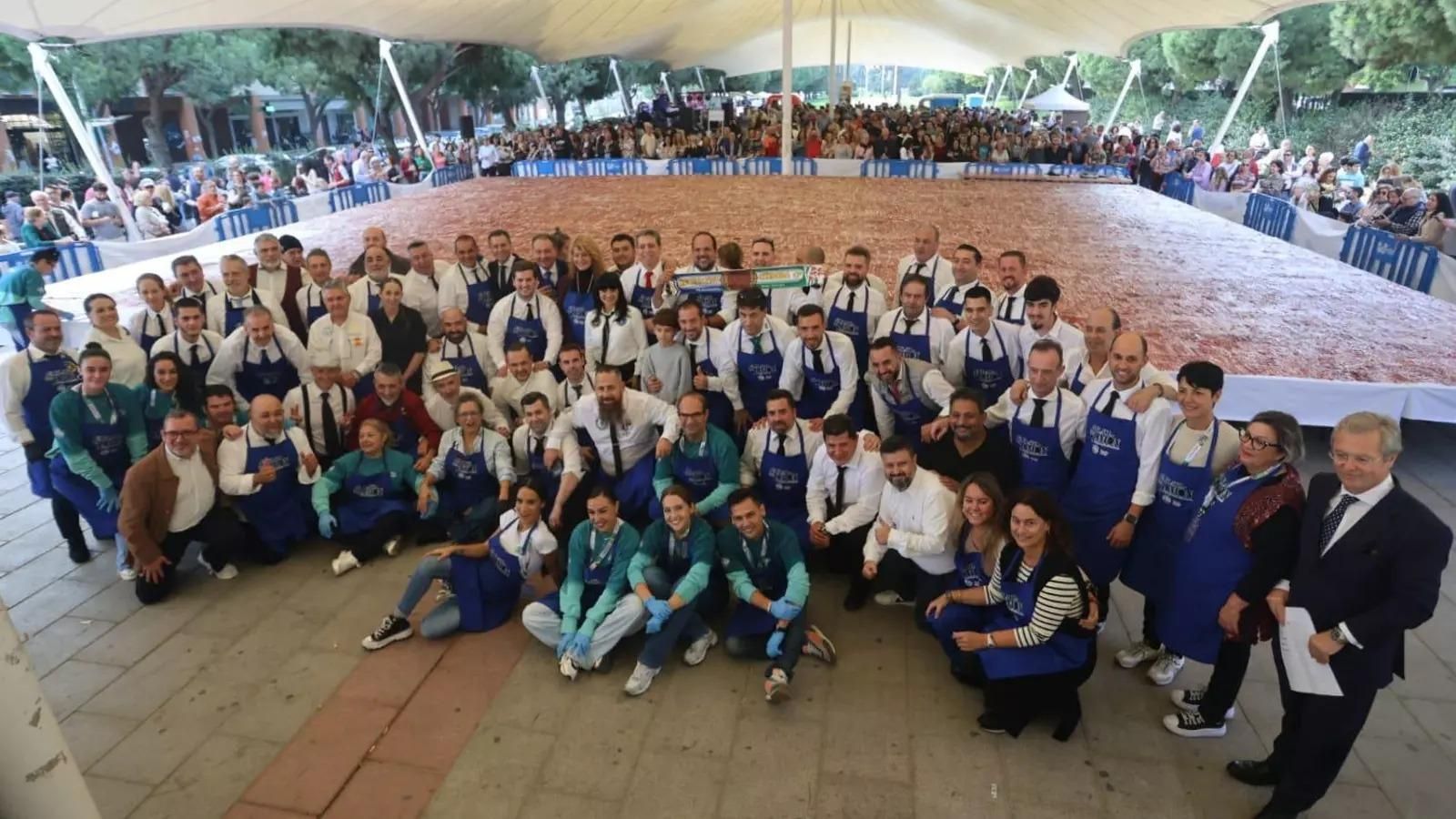 Equipo de cortadores y representantes institucionales de Huelva posan junto al plato de jamón que batió el récord Guiness en 2024.