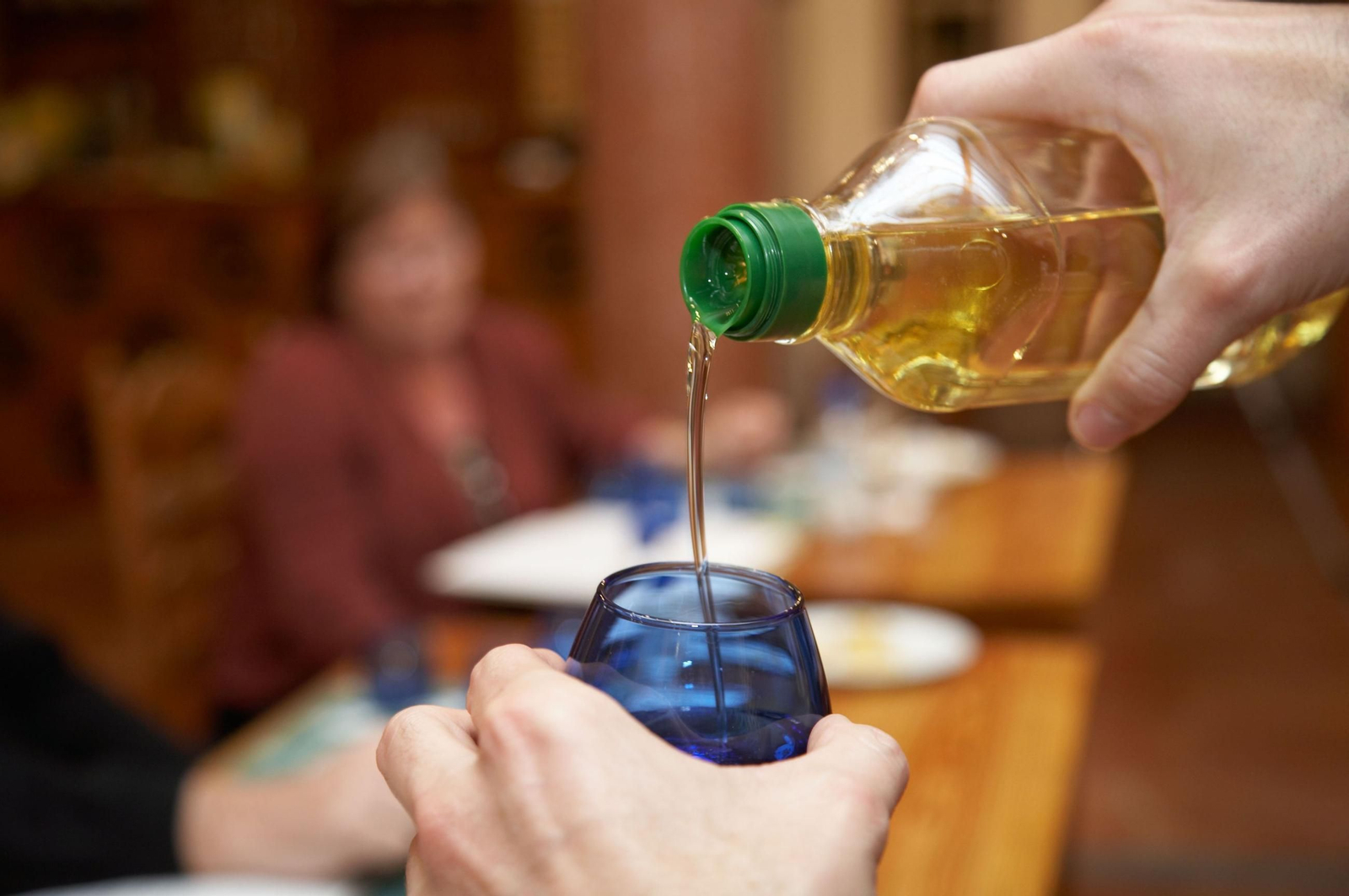 Una persona sirve aceite de oliva en un vaso para un comensal.