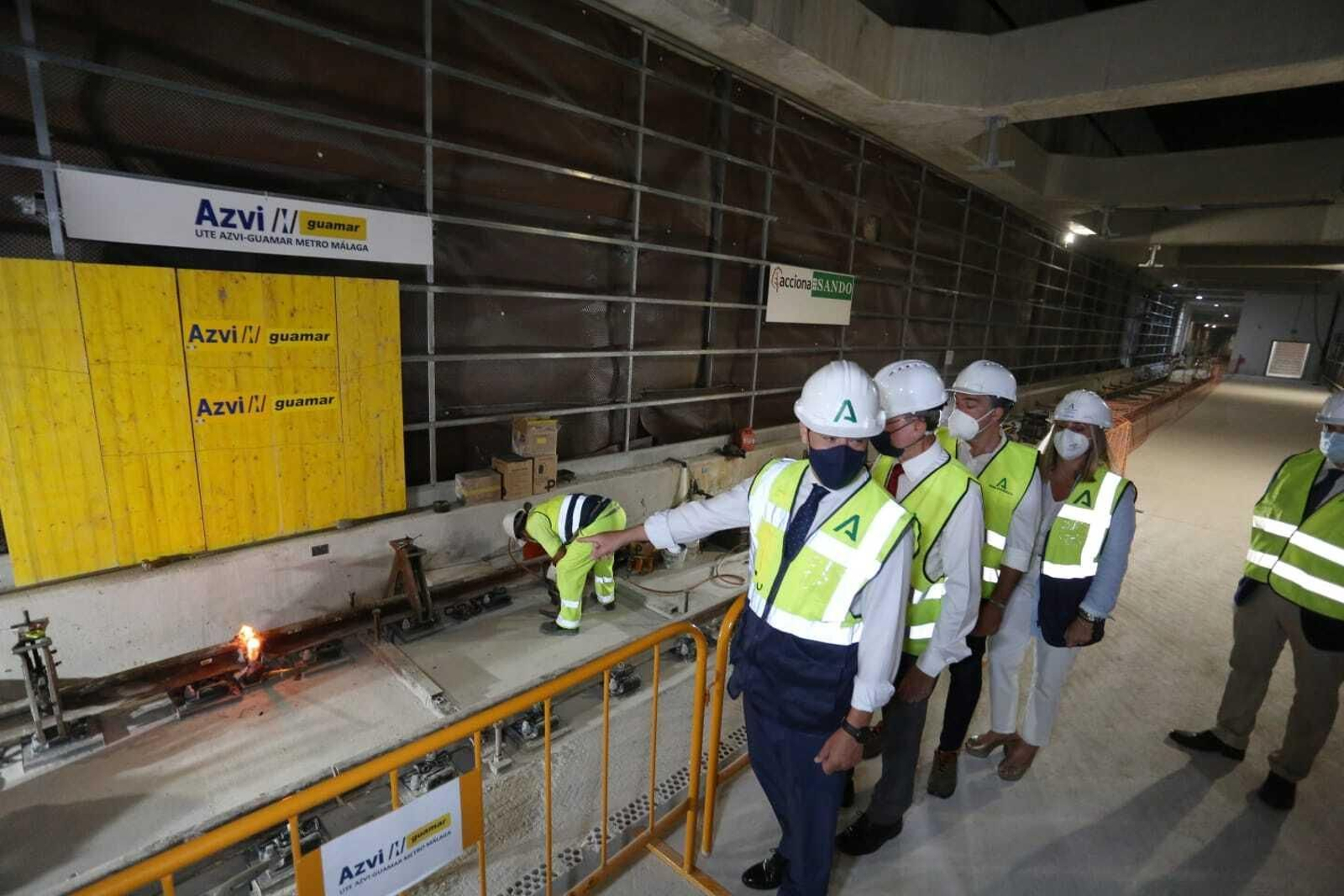 Juan Manuel Moreno Bonilla señala a un operario en el Metro de Málaga junto a otras autoridades.