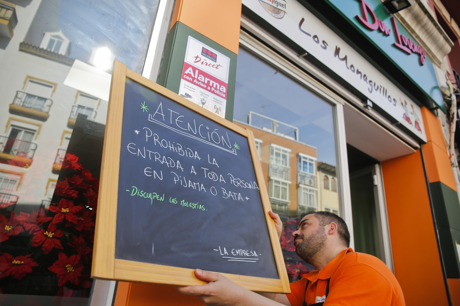 Un camarero coloca un cartel en el bar Los Monaguillos.