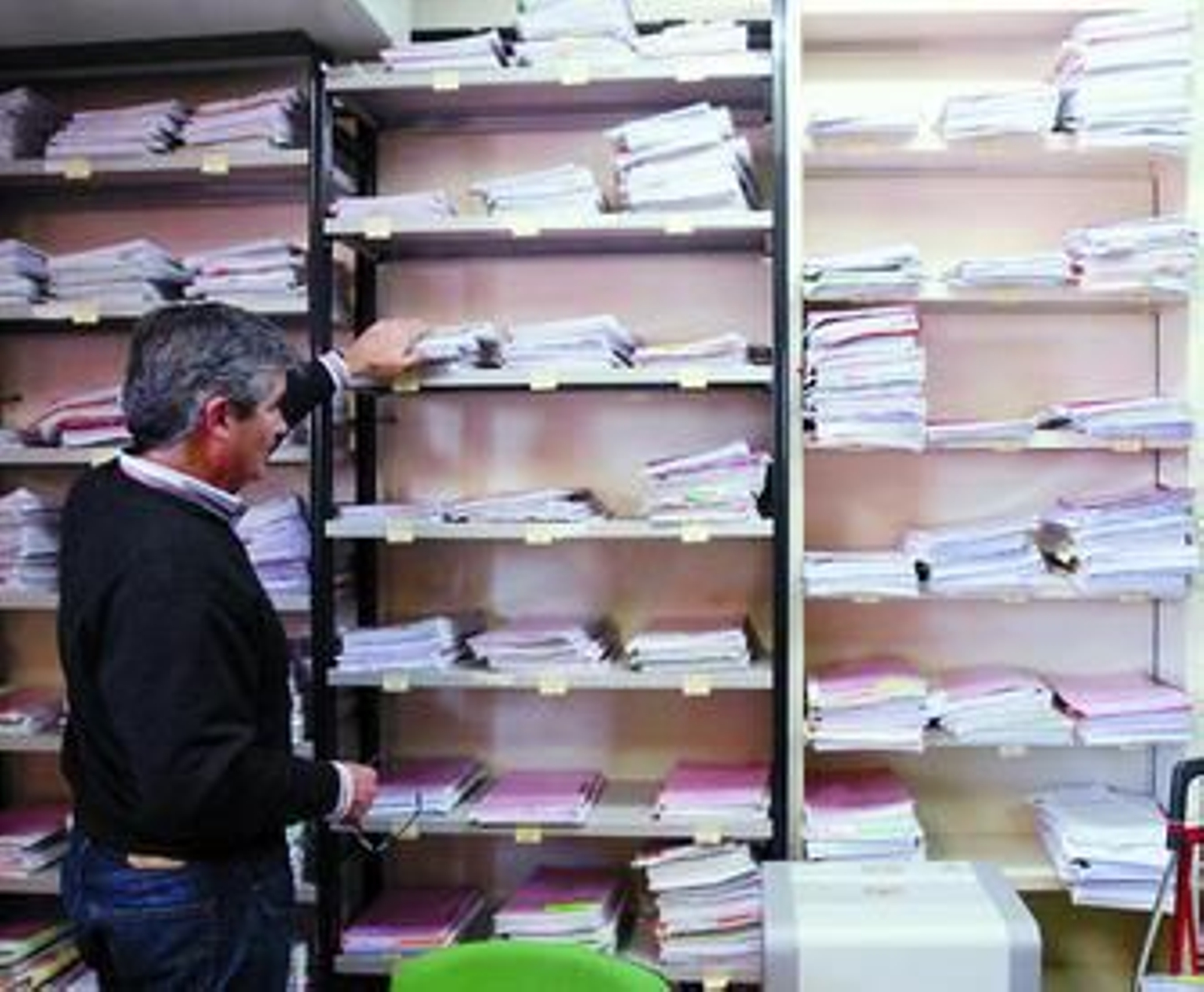 Un funcionario, ante una estantería llena de expedientes.