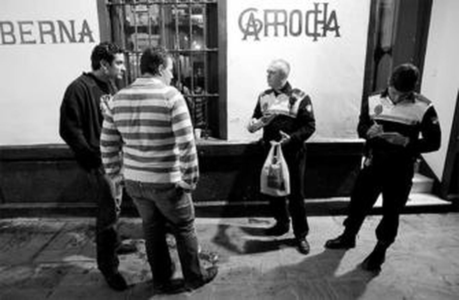 Una pareja de municipales requisan un 'botellón' y multan a varios ciudadanos en la Plaza Mitjana, el pasado jueves por la noche.