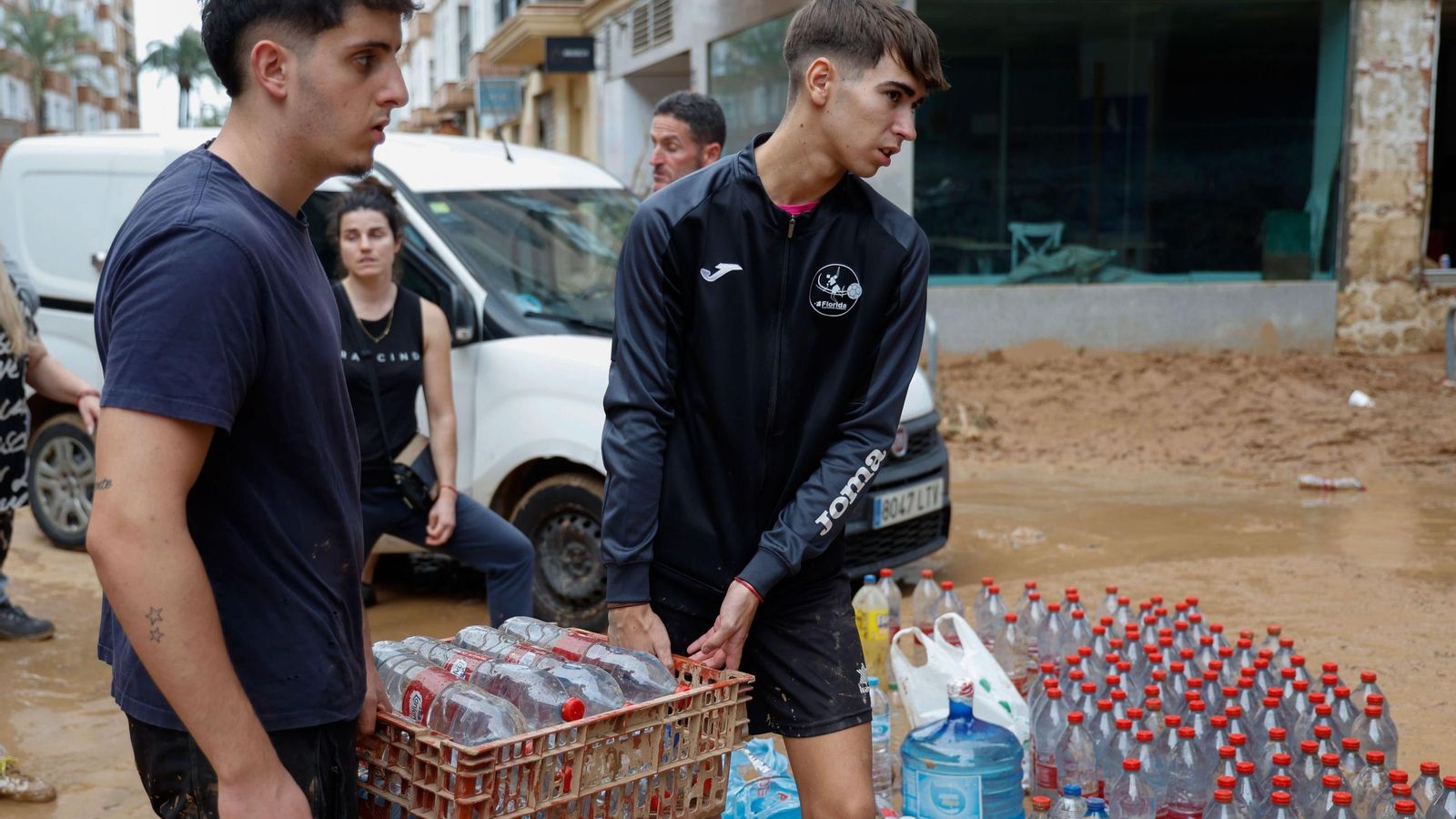 Varias personas reparten botellas de agua este jueves en Paiporta (Valencia).
