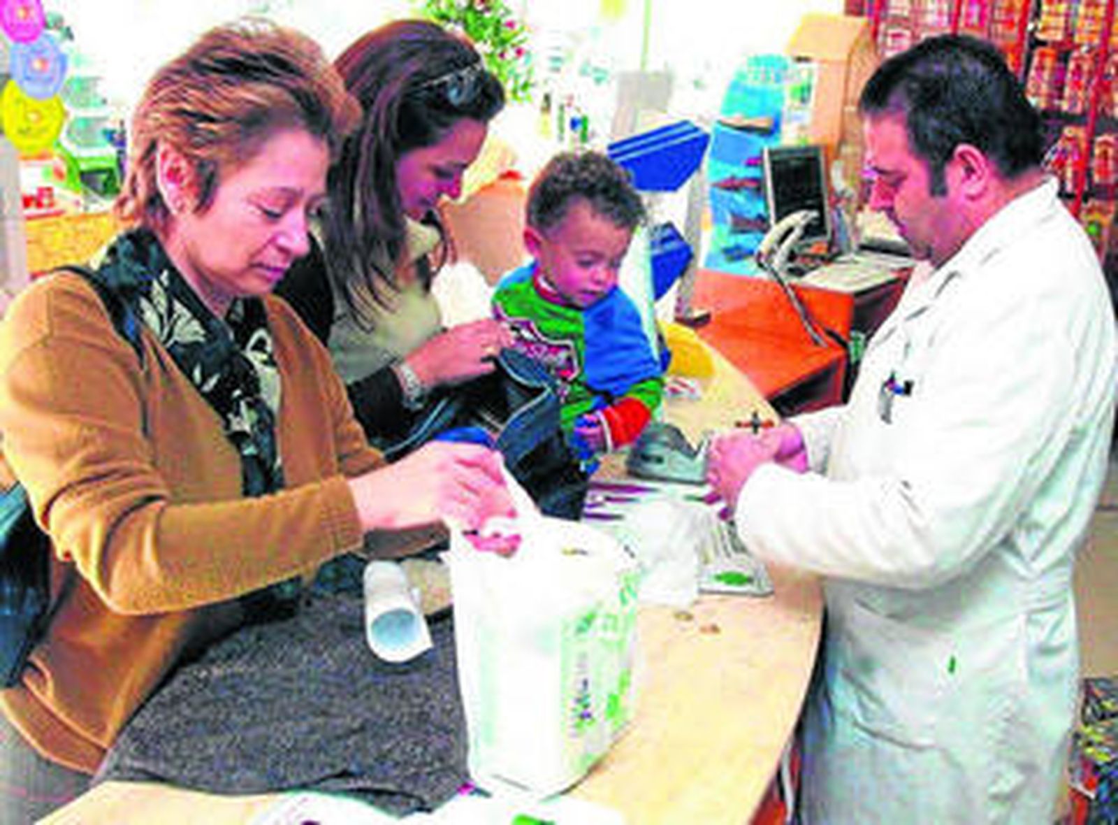 Una familia adquiere en la farmacia medicamentos para los más pequeños.