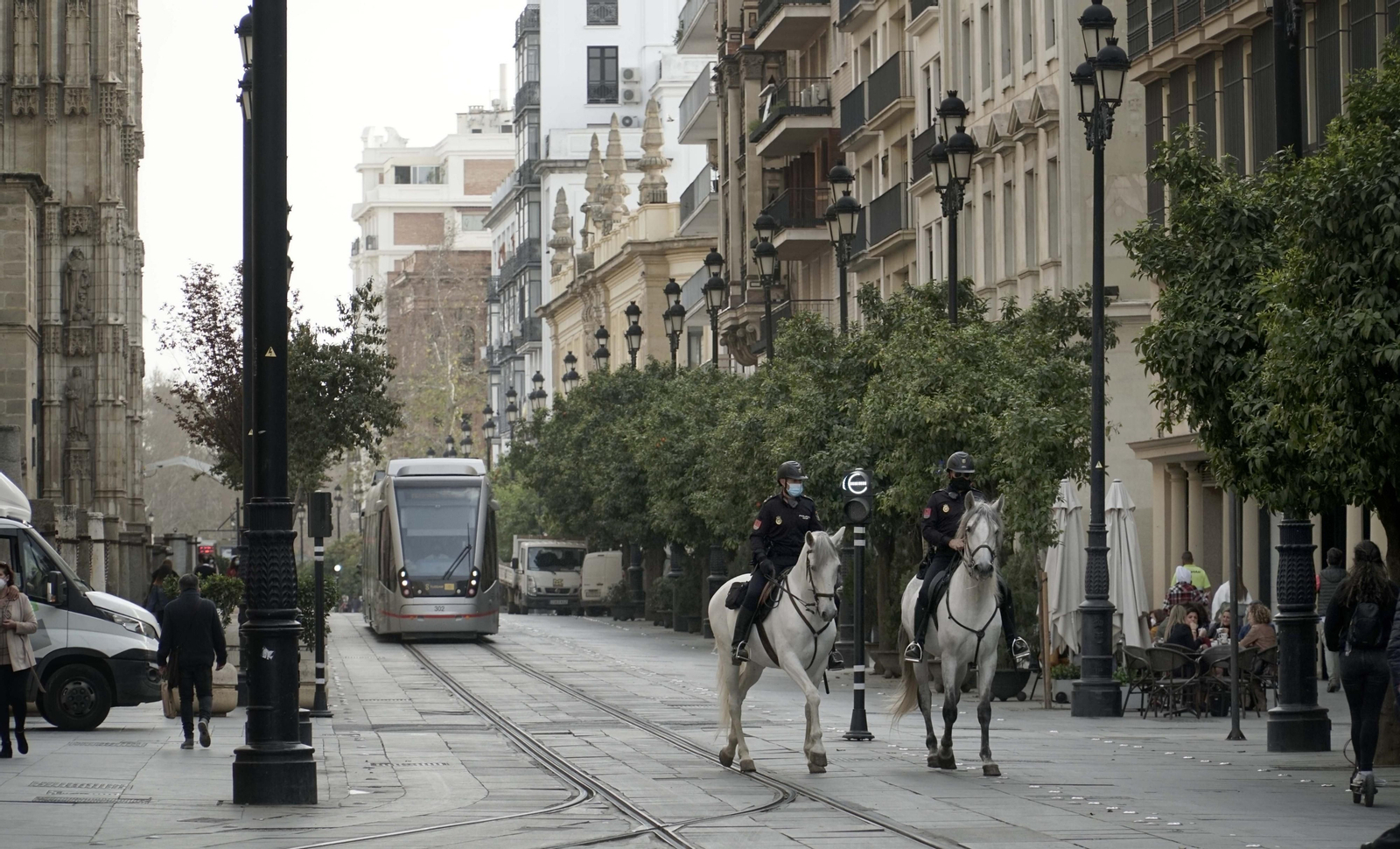 Una pareja de la Policía Nacional a caballo patrulla por la Avenida de la Constitución con el tranvía al fondo.