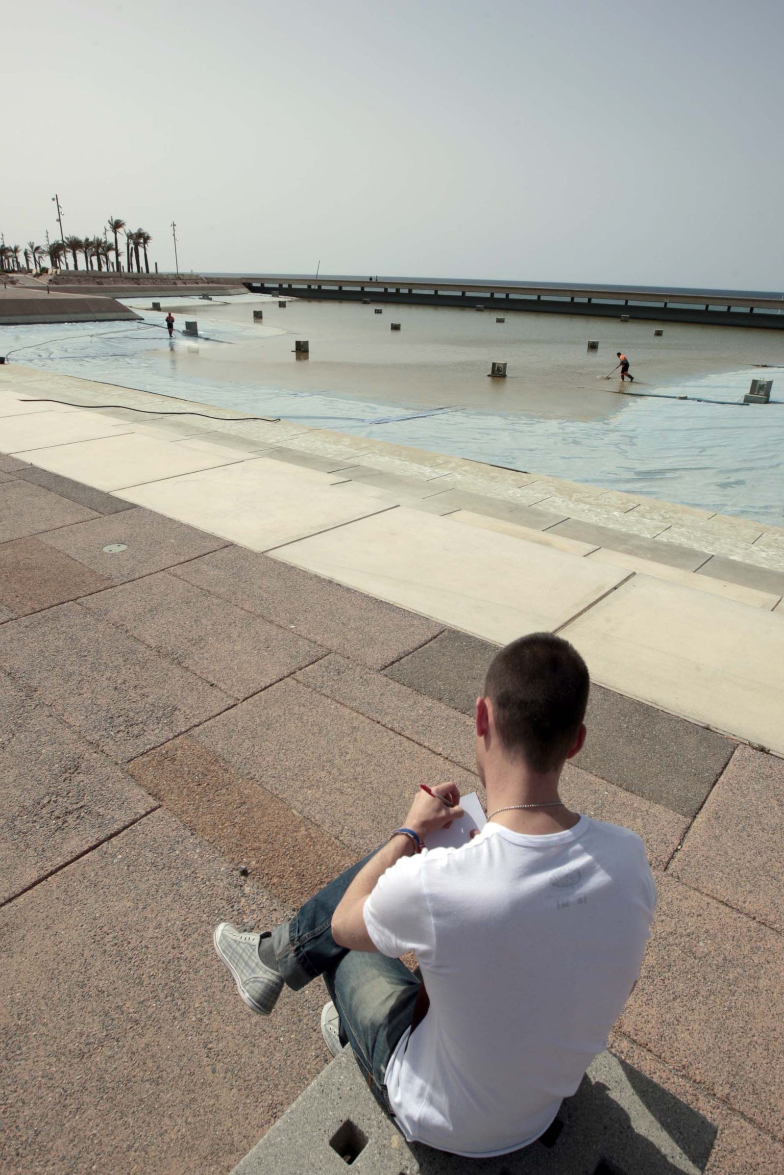 Un hombre observa las tareas de limpieza de la balsa.