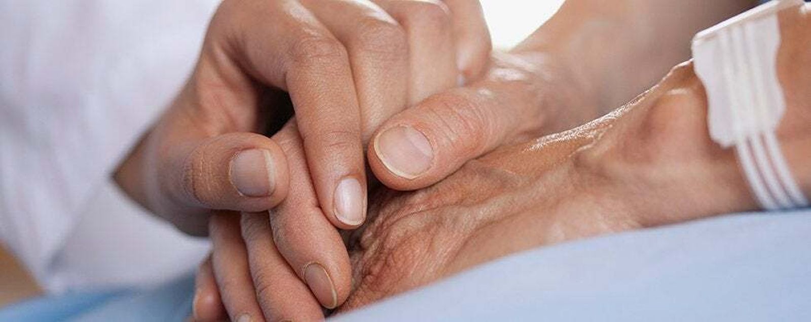 Un familiar estrecha la mano de un enfermo