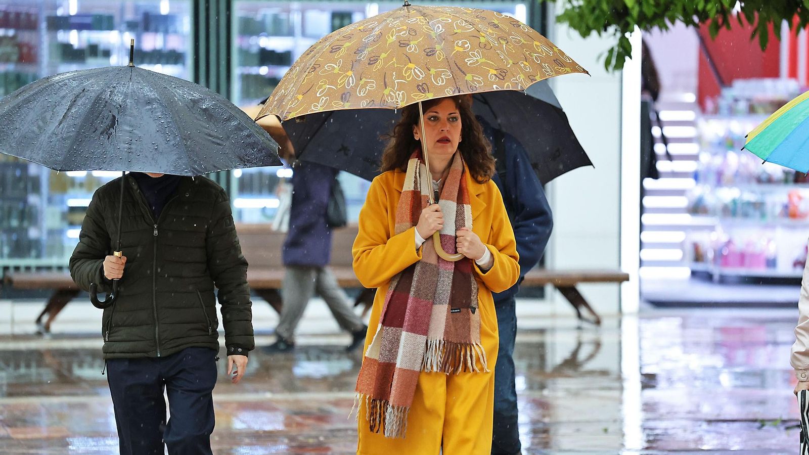 Personas se refugian de la lluvia con paraguas en Huelva.