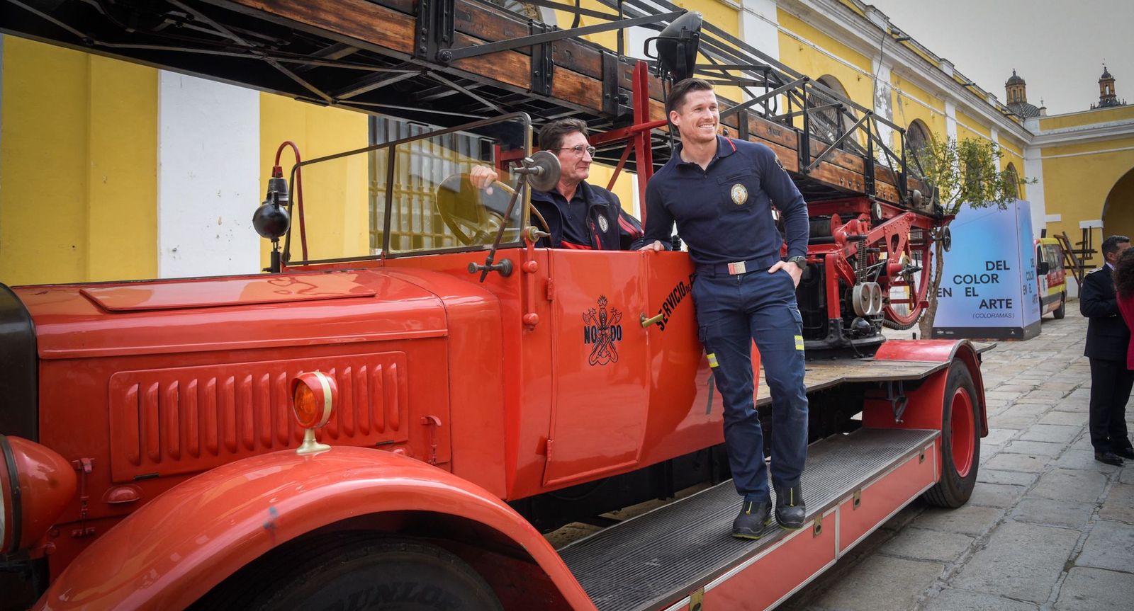 Juan Jesús Casas y su hijo, David, bomberos de Sevilla, con un vehículo antiguo del cuerpo.