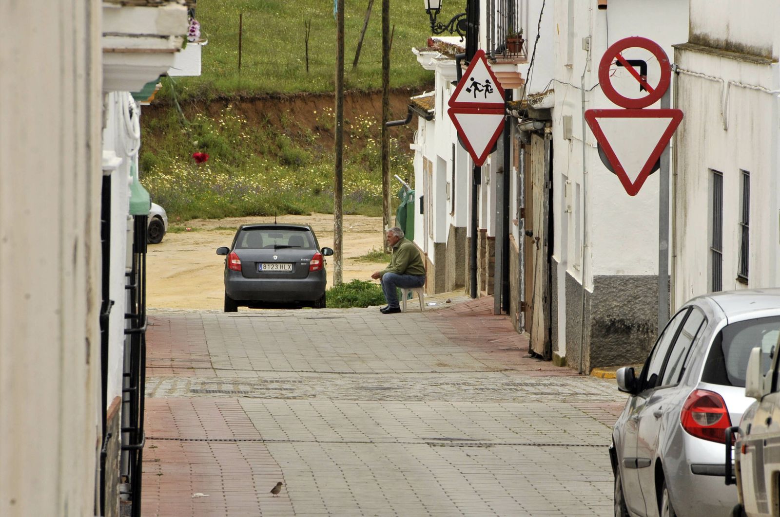 Un vecino de Algar sentado ante la puerta de su casa en una de sus calles.