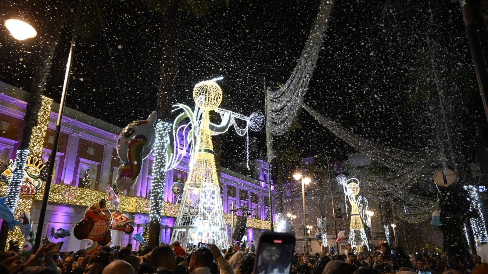Los onubenses disfrutan de la nevada artificial durante el encendido del alumbrado de Navidad.