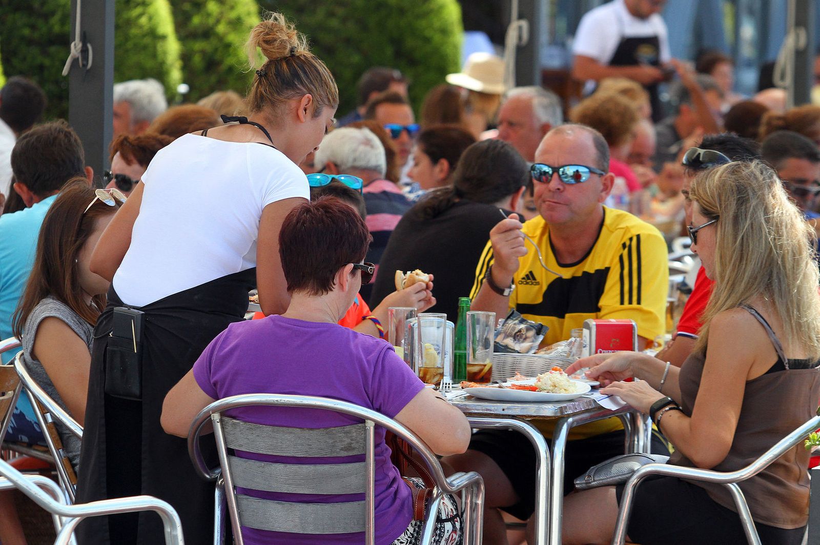 Una camarera atiende una mesa en una terraza andaluza.