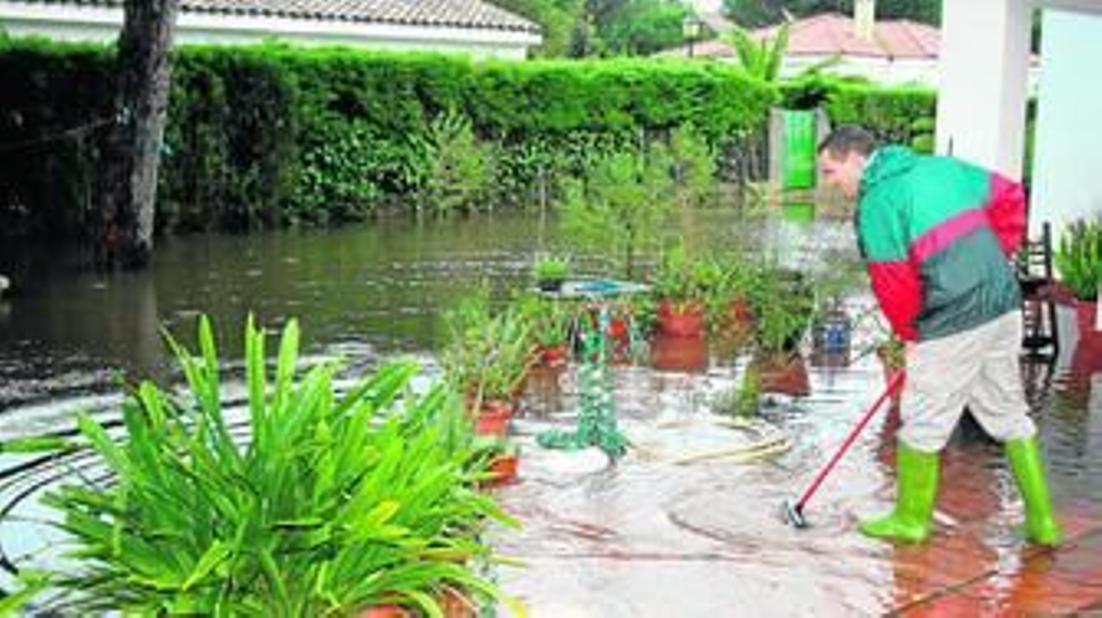 Uno de los vecinos de la urbanización de Roche, en Conil, achica agua de su vivienda anegada.