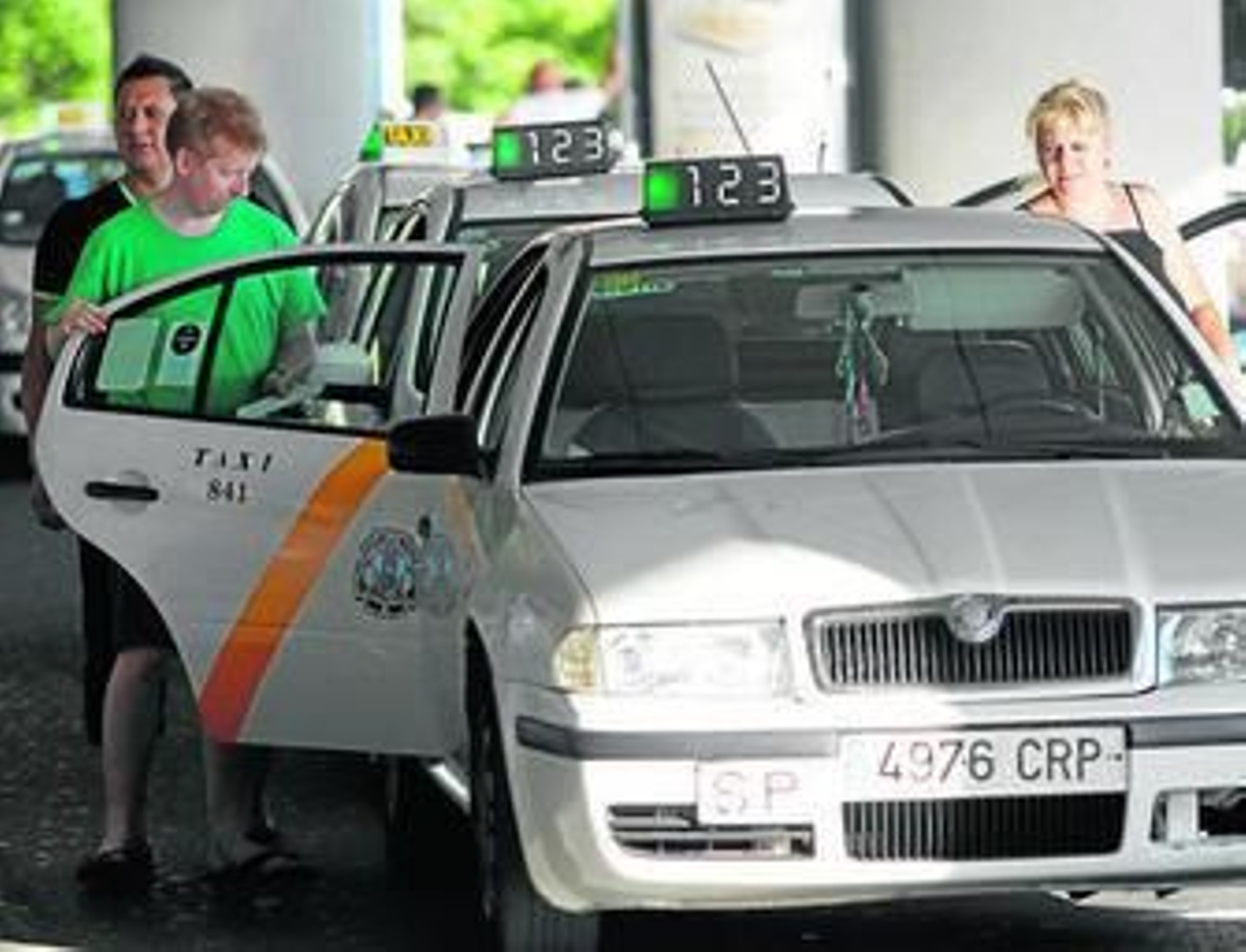 Dos usuarios se disponen a montarse en un taxi.