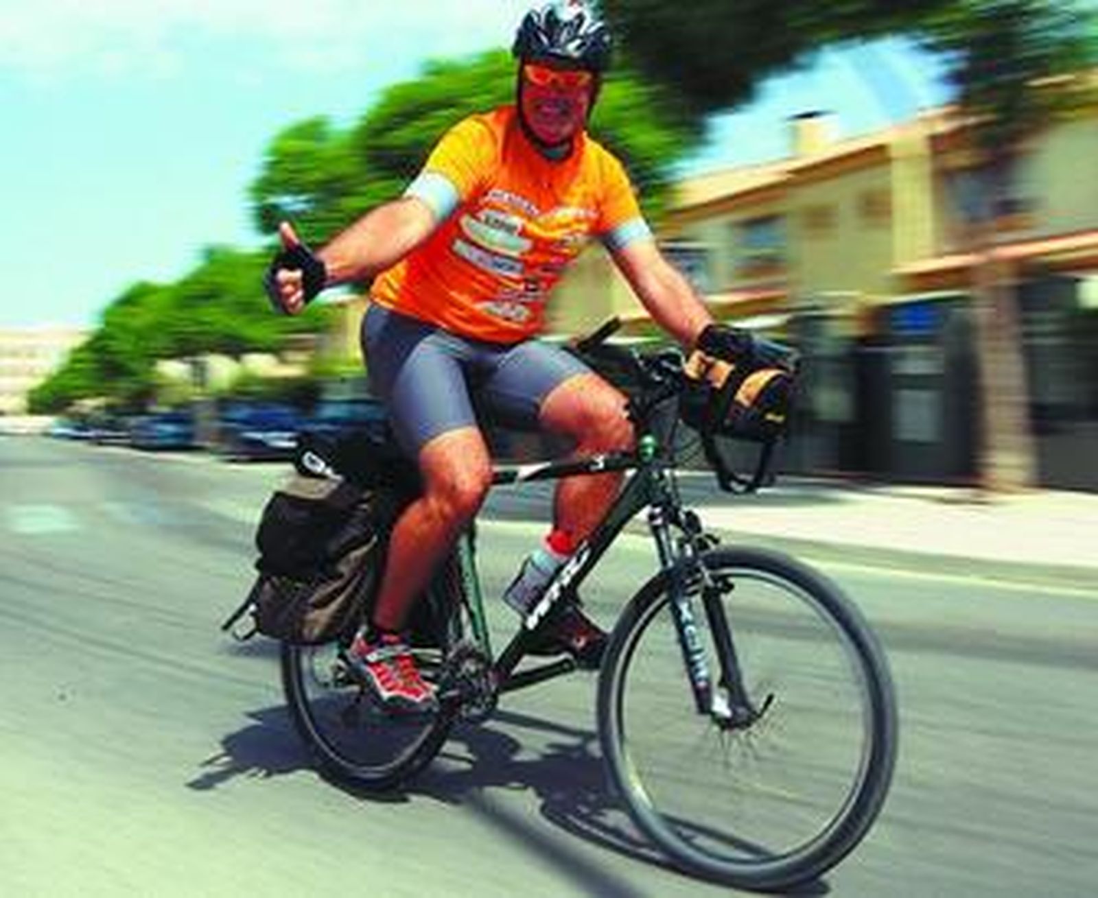 El aficionado saluda desde su bicicleta, a la que mima a diario.