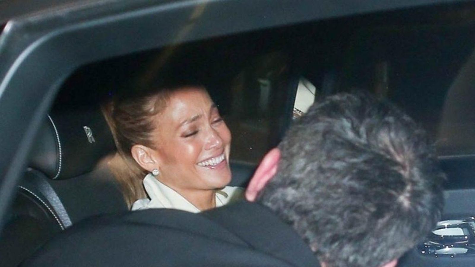 La cantante se ríe a bordo del coche mientras Affleck da la espalda a los paparazzi.