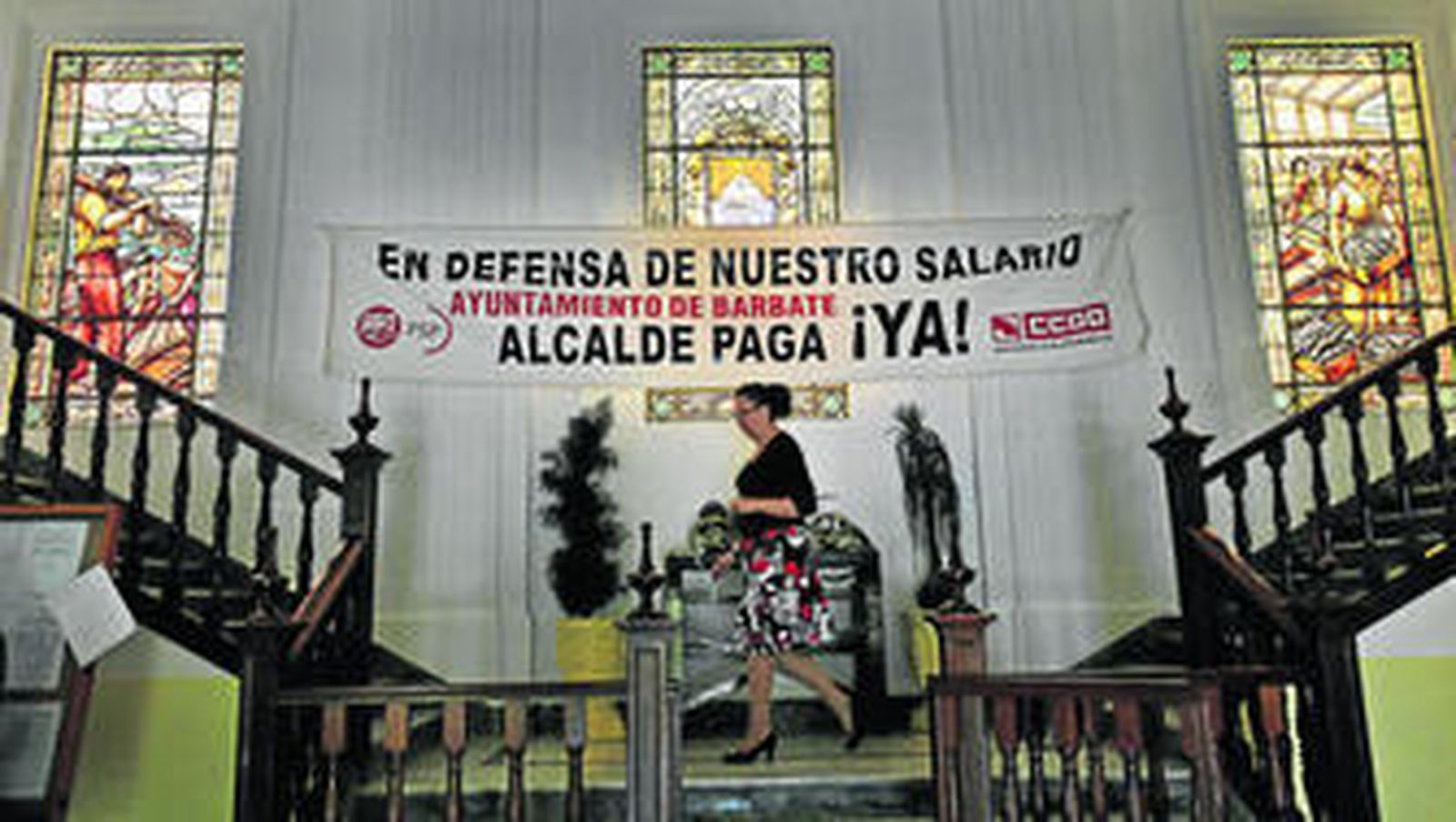 Una mujer pasa ante la pancarta reivindicativa de los trabajadores municipales de Barbate, en el Ayuntamiento.