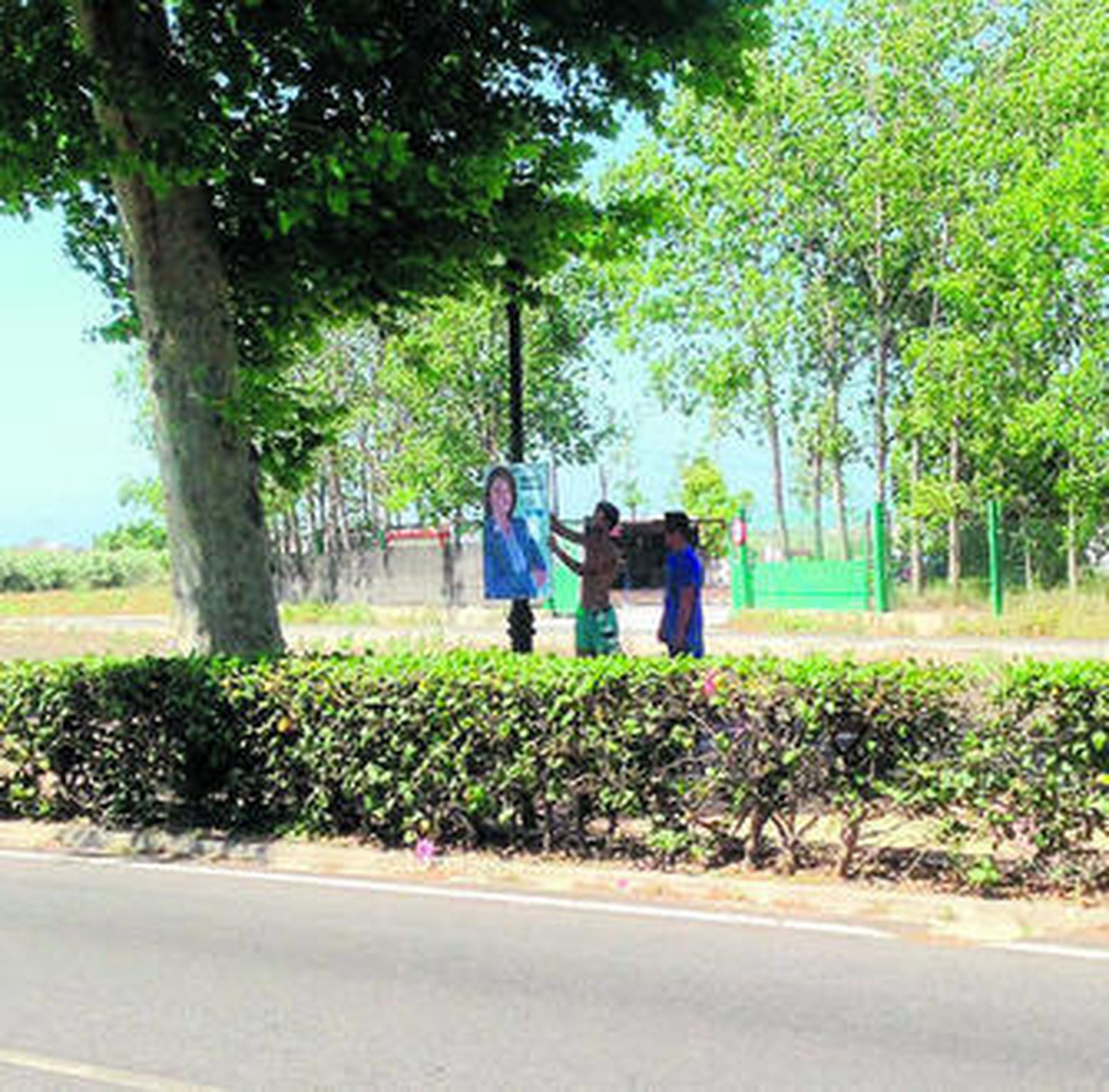 Dos jóvenes quitando carteles de Luisa García Chamorro.