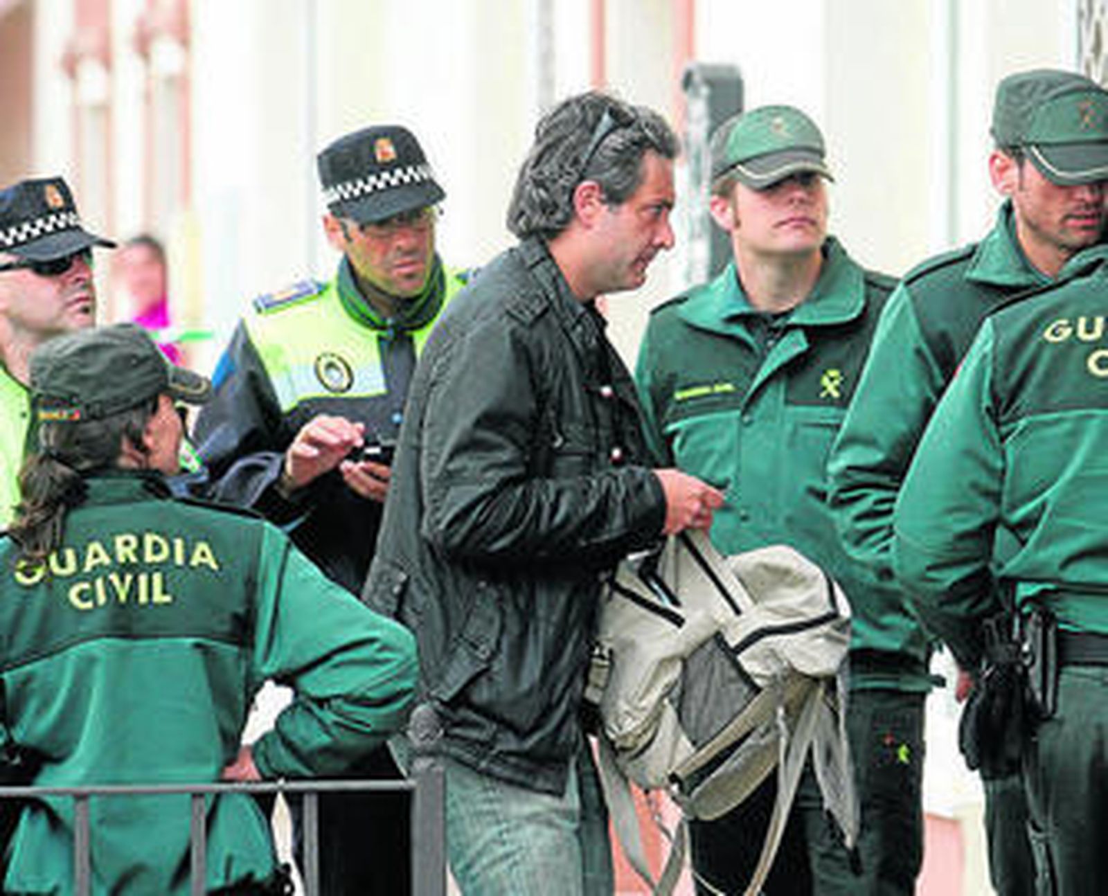 Un forense, en el centro, llega a la casa donde fueron encontrados los cuerpos, rodeado de agentes.