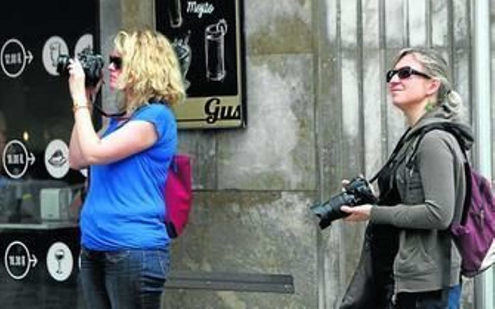 Dos turistas toman fotos de una escena de la ciudad en Semana Santa.