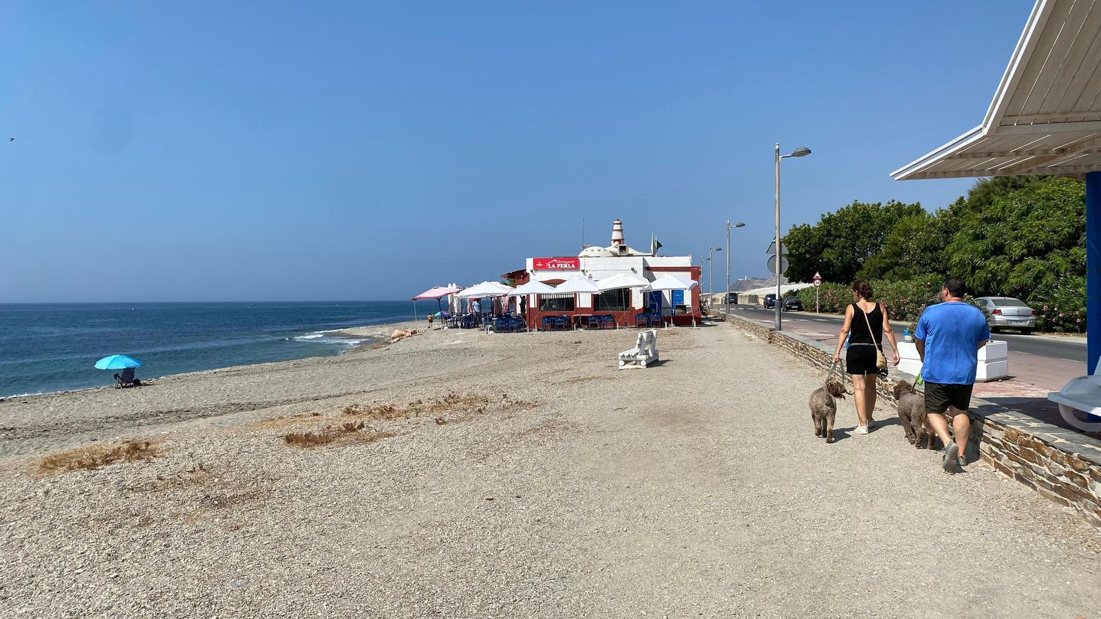 Dos personas pasean por la playa practicamente vacía