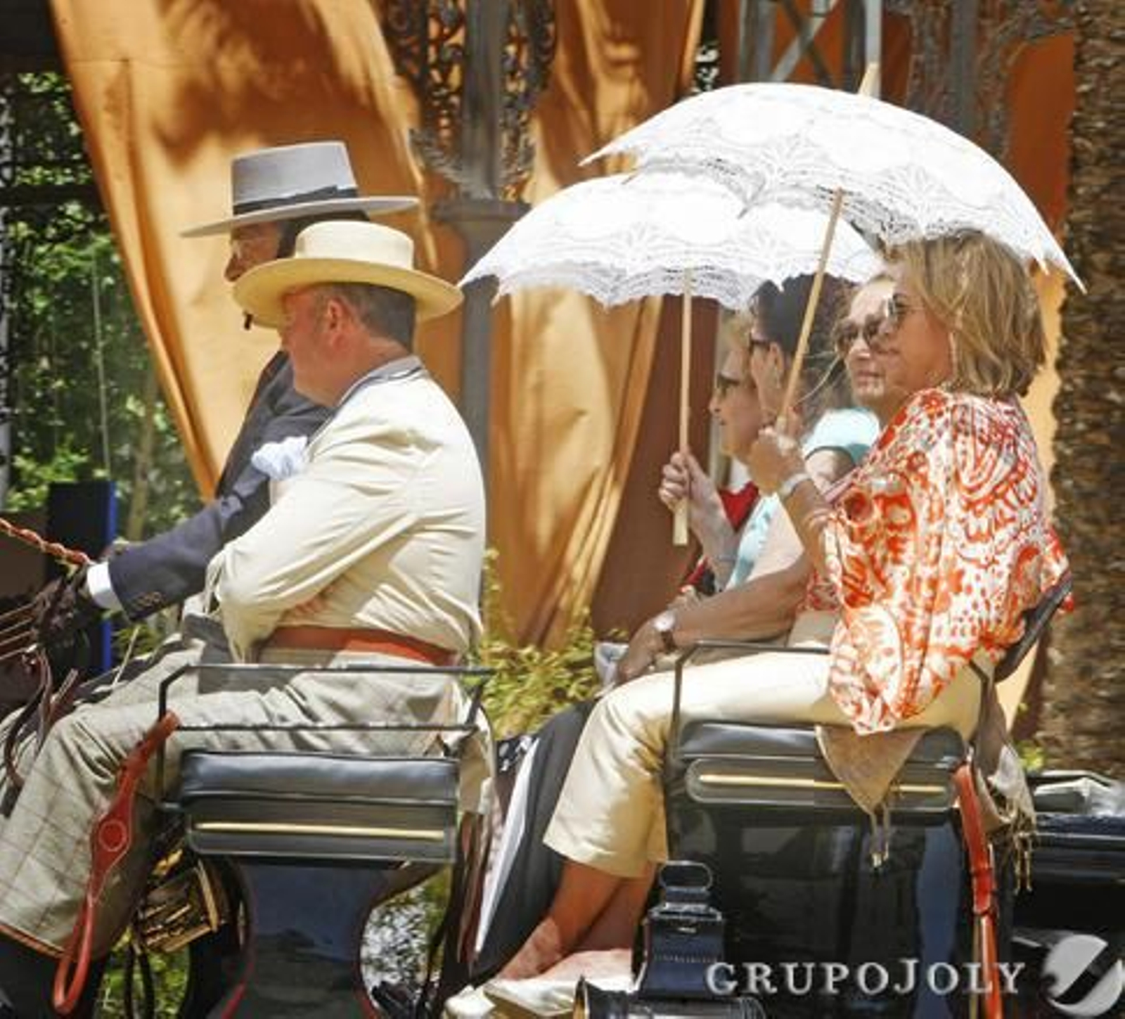 Un grupo se protege del sol con unos paraguas en un carruaje.

Foto: Pascual