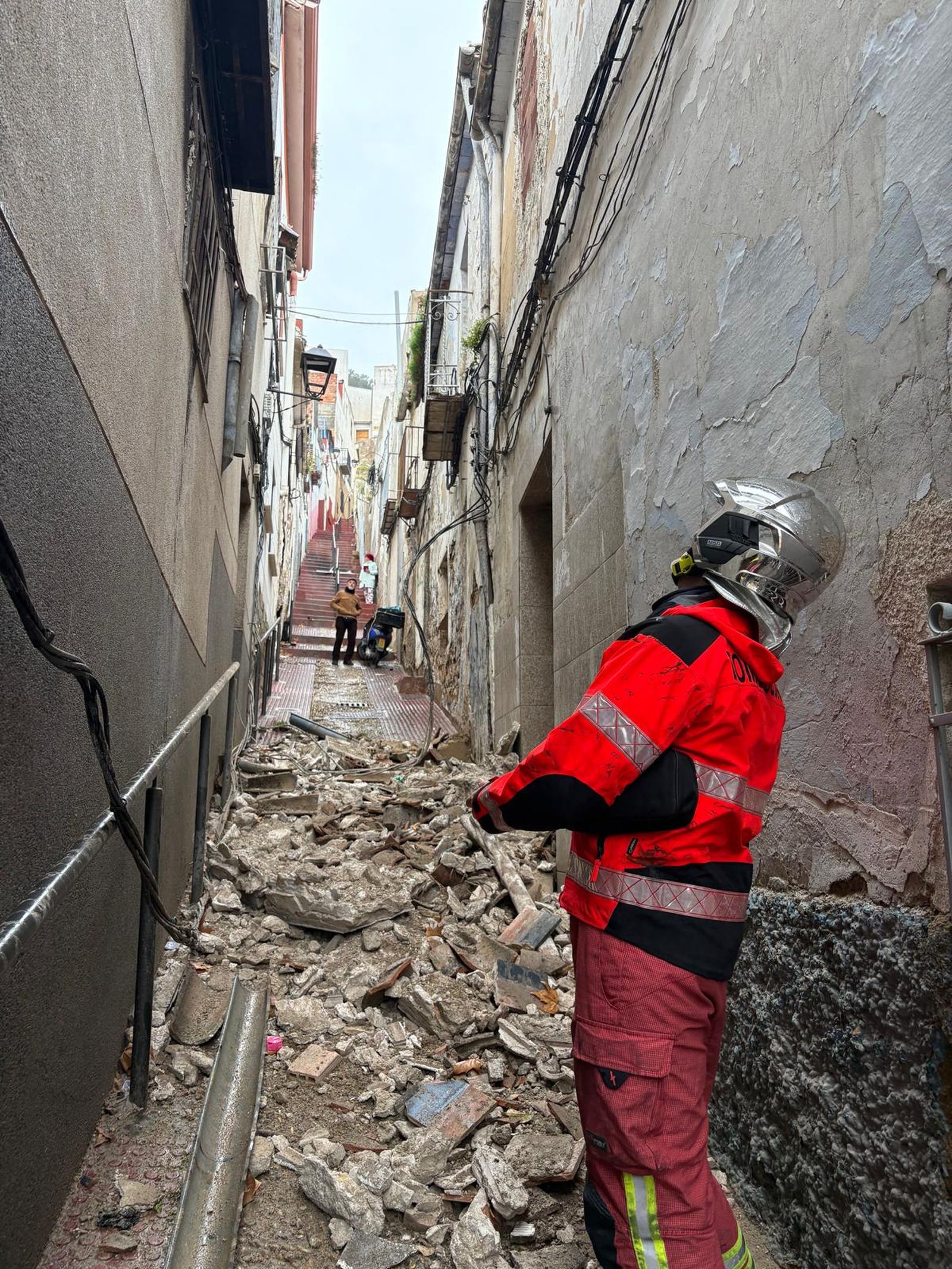 Un bombero observa la caída de un lienzo de una pared en el centro de Jaén.