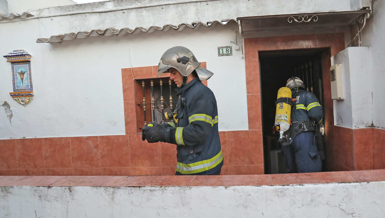 Bomberos salen de la casa afectada por el fuego la tarde-noche de este domingo.