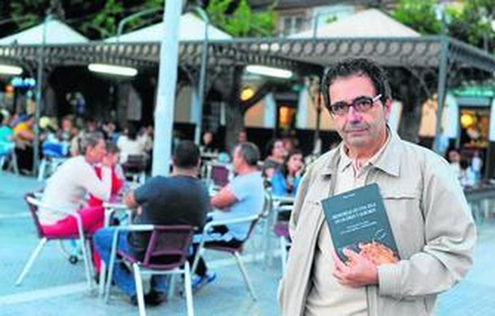 Pepe Oneto posa en la calle Real con su libro sobre la herencia gastronómica de La Isla.