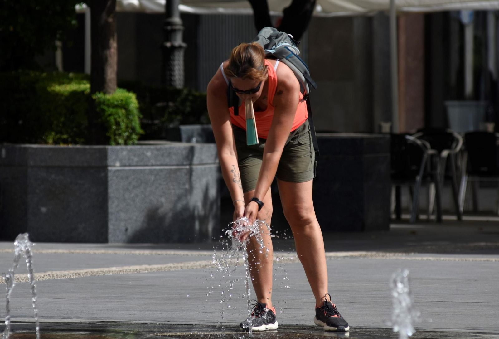Una mujer se refresca en una fuente.