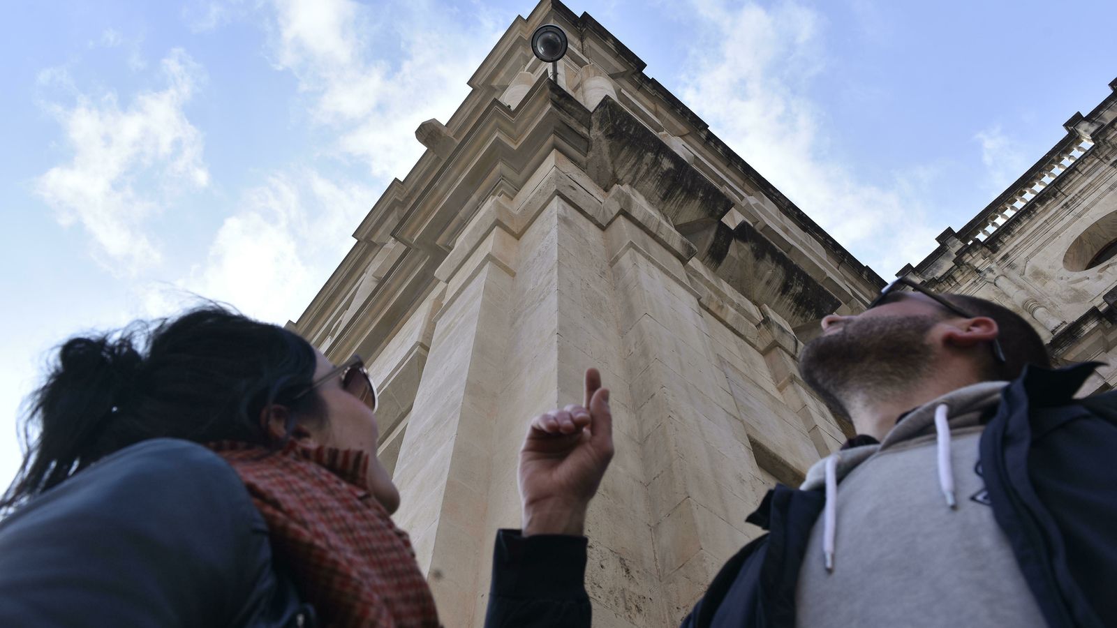 Una pareja observa una de las cámaras del Ayuntamiento de Sevilla.