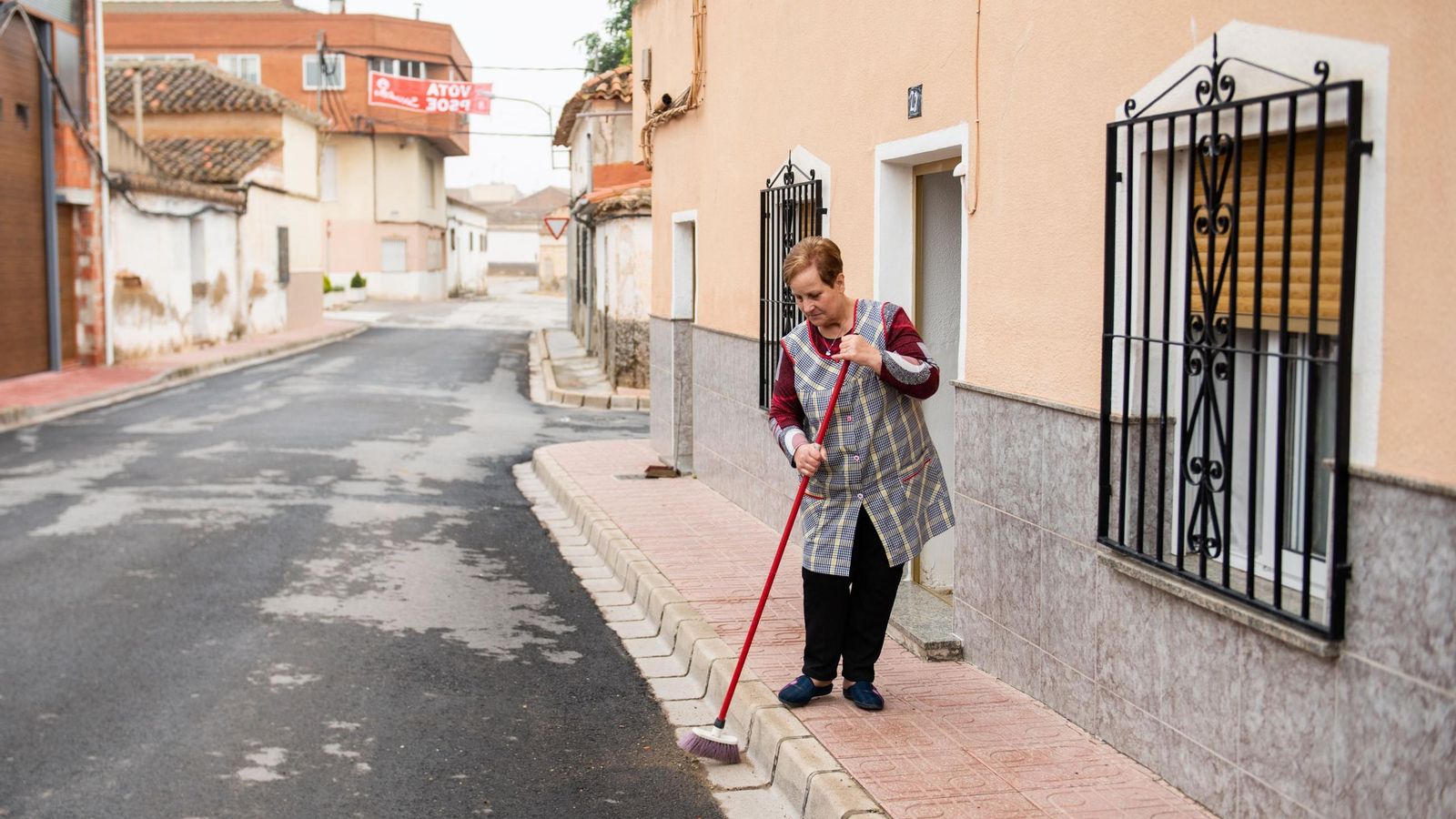 Una mujer barre en la puerta de su casa en un municipio del interior de Almería.