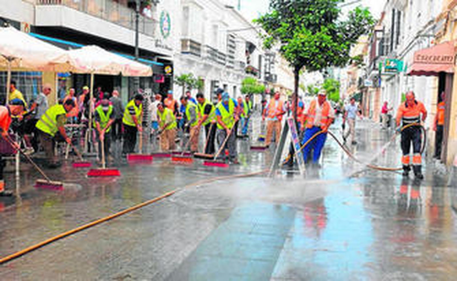 Un nutrido grupo de operarios limpiando ayer la céntrica calle San Juan después de la tromba de agua.