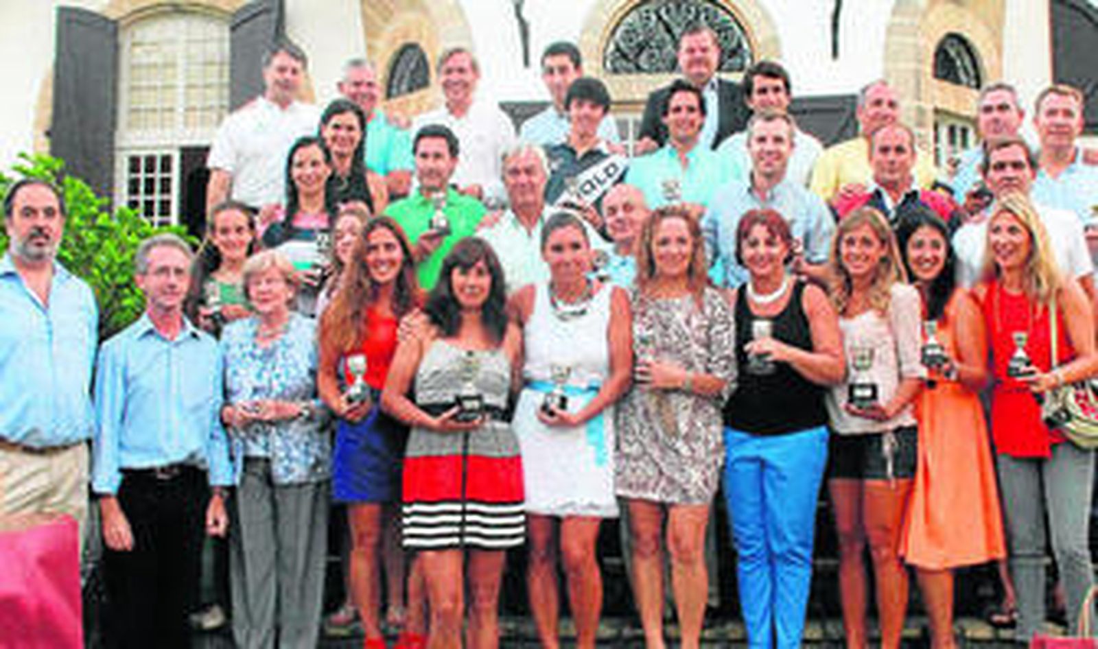 Los ganadores de los torneos de tenis y pádel posan con sus trofeos.