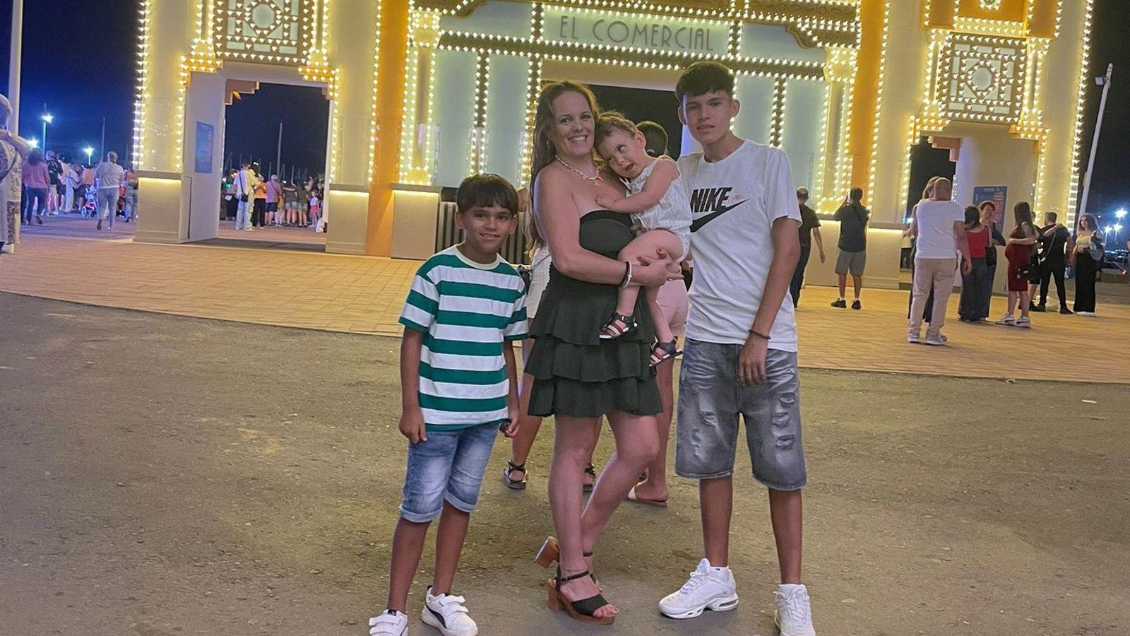 Candy junto a Aarón y sus otros dos hijos frente a la portada de las Fiestas Colombinas.